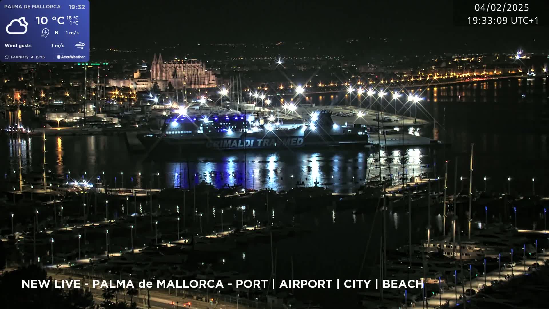 A nighttime harbor scene shows a large ship, many smaller boats in a marina, and a city skyline in the background under a partly cloudy sky.