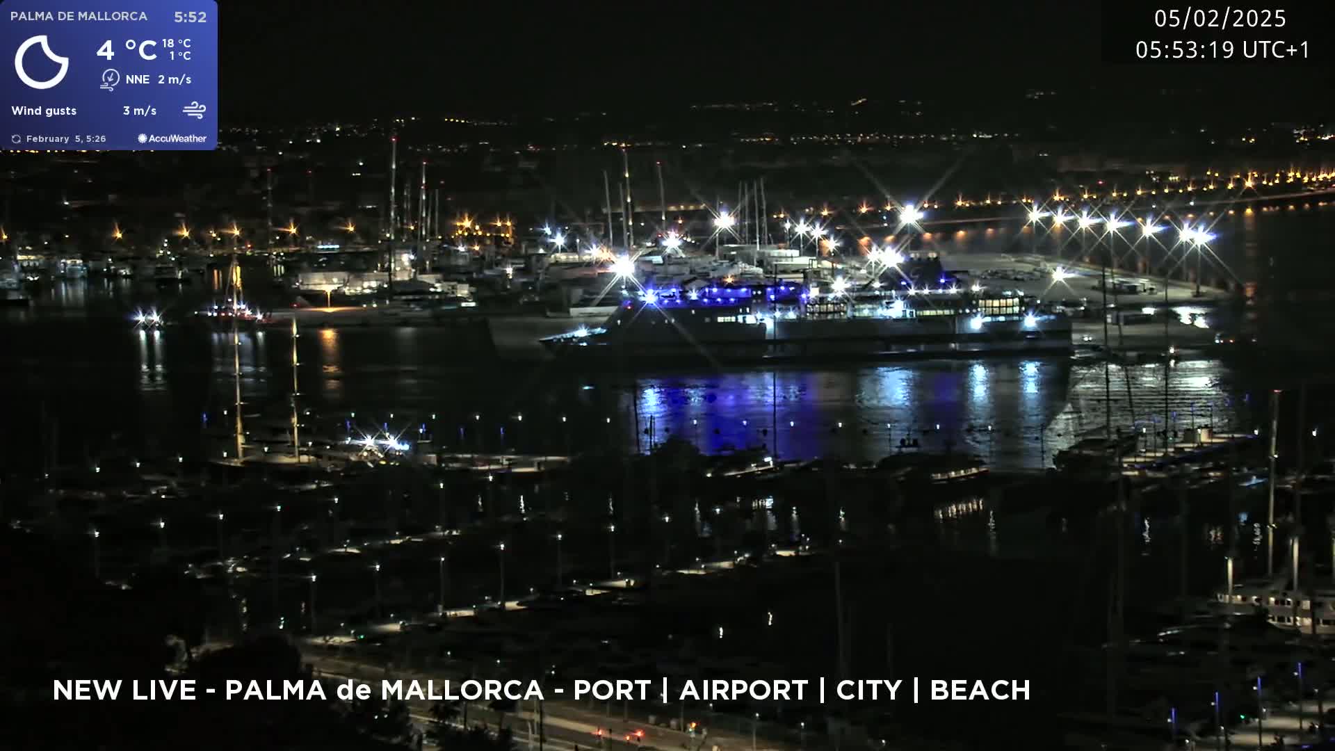 A nighttime, aerial view of a harbor filled with boats and a large ferry, under a clear sky.