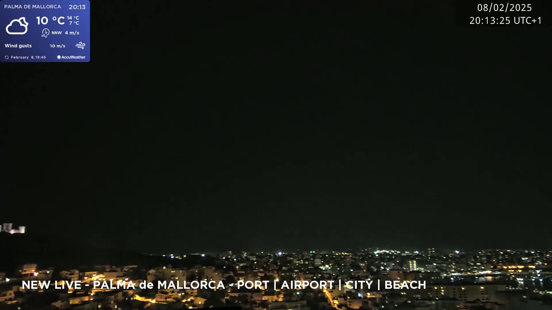A nighttime view of a city illuminated by lights under a mostly clear, dark sky.