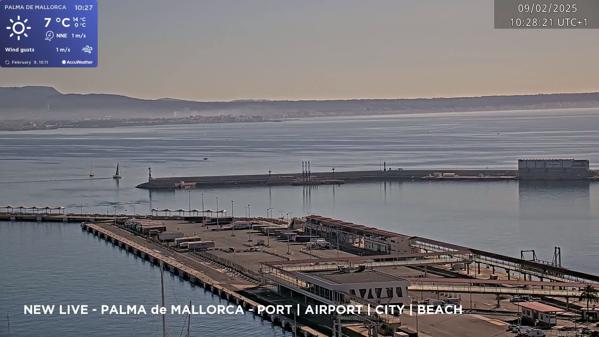 A harbor with docked ships and trucks under a mostly clear, sunny sky.