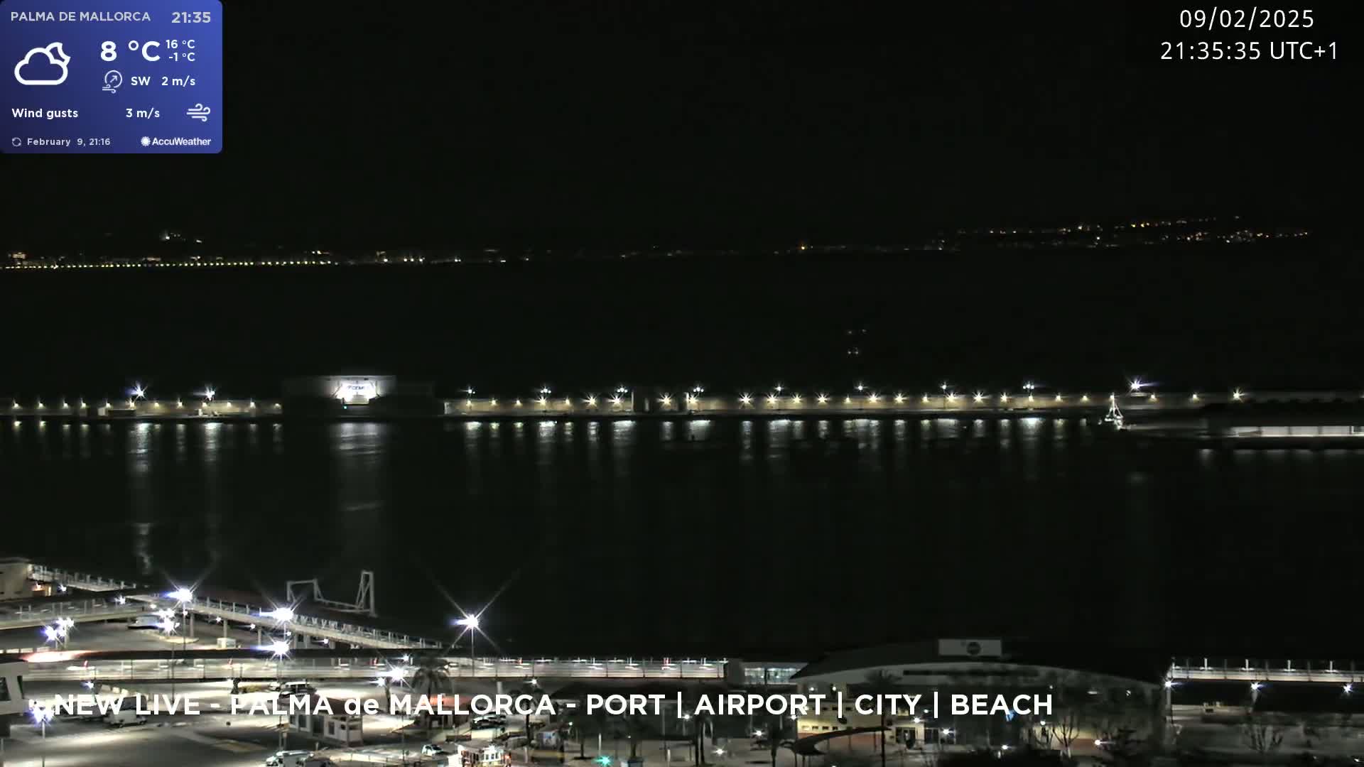 A nighttime view of a calm body of water with illuminated structures along its edge, under a clear sky.