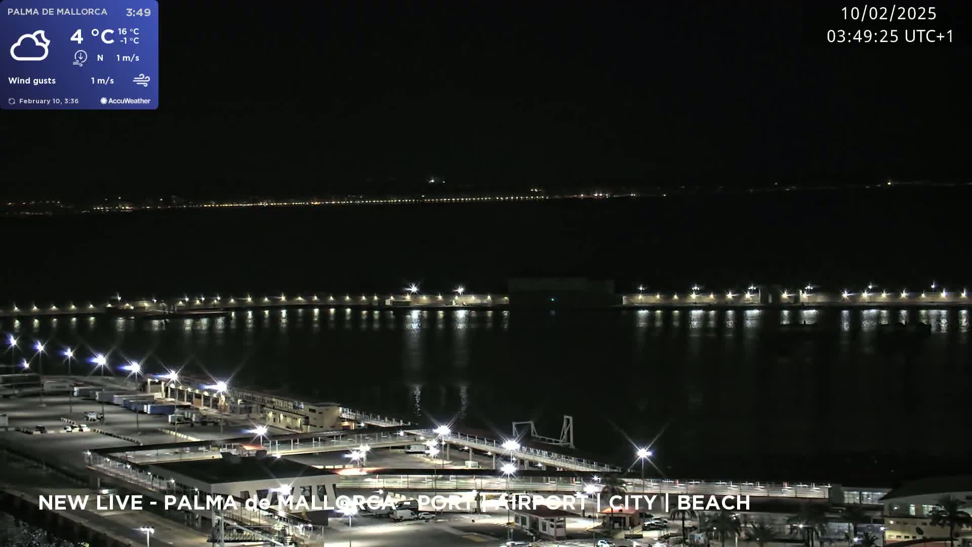 A nighttime view of a port area with calm water, illuminated by lights, under a cloudy sky.