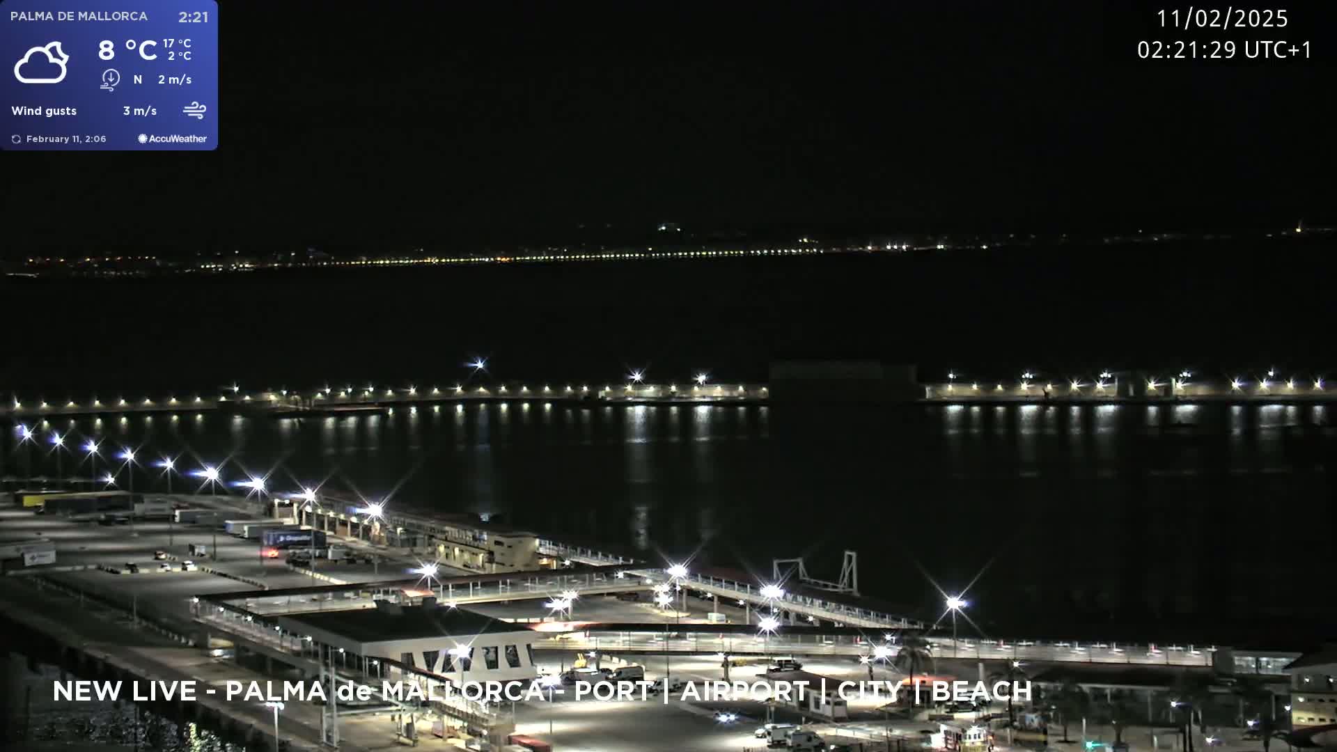 A nighttime view of a port area with lights illuminating the docks and surrounding buildings, under partly cloudy skies with a temperature of 8°C.