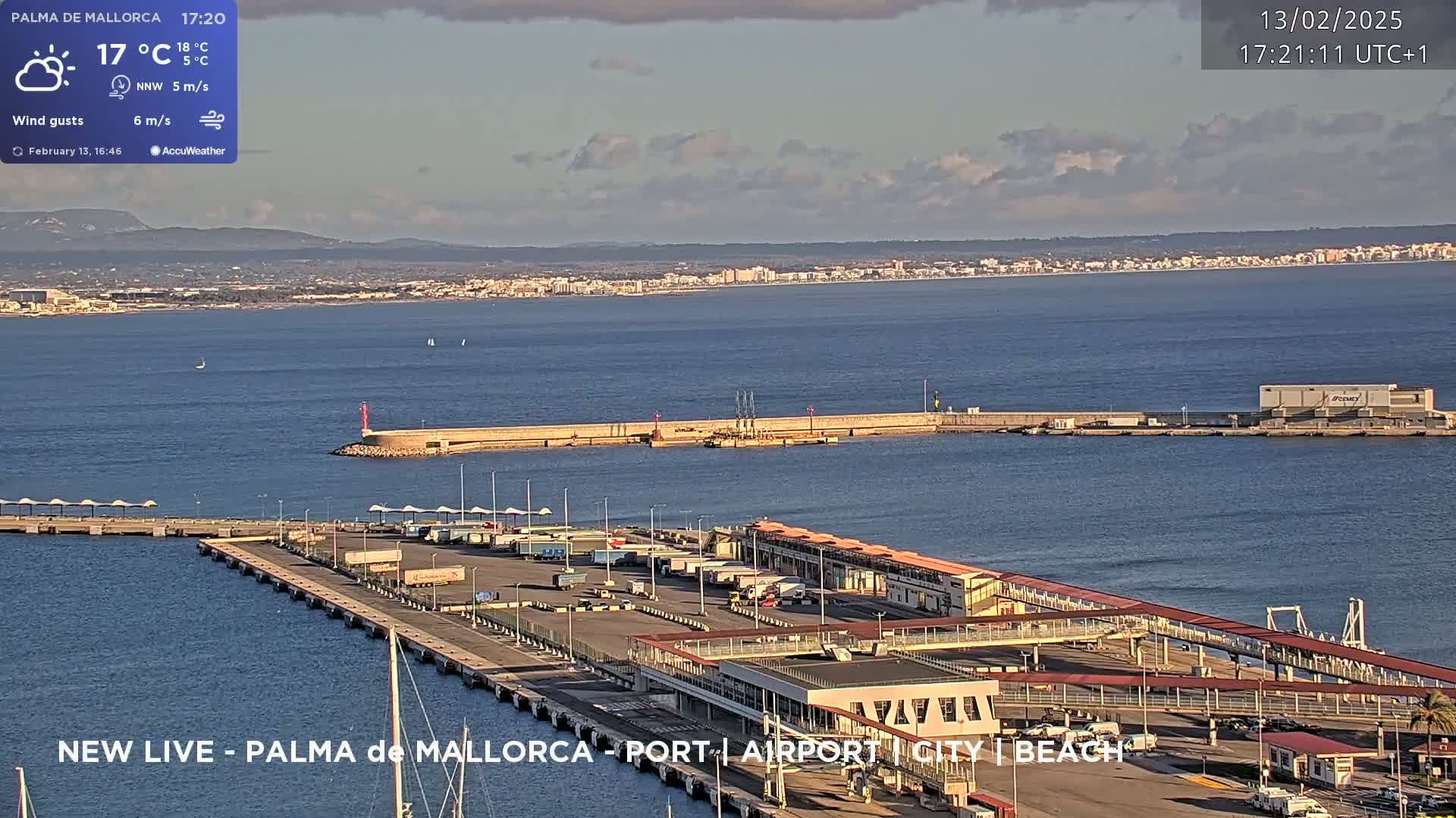 A partly cloudy harbor scene shows a port with buildings and vehicles under a mostly clear sky.