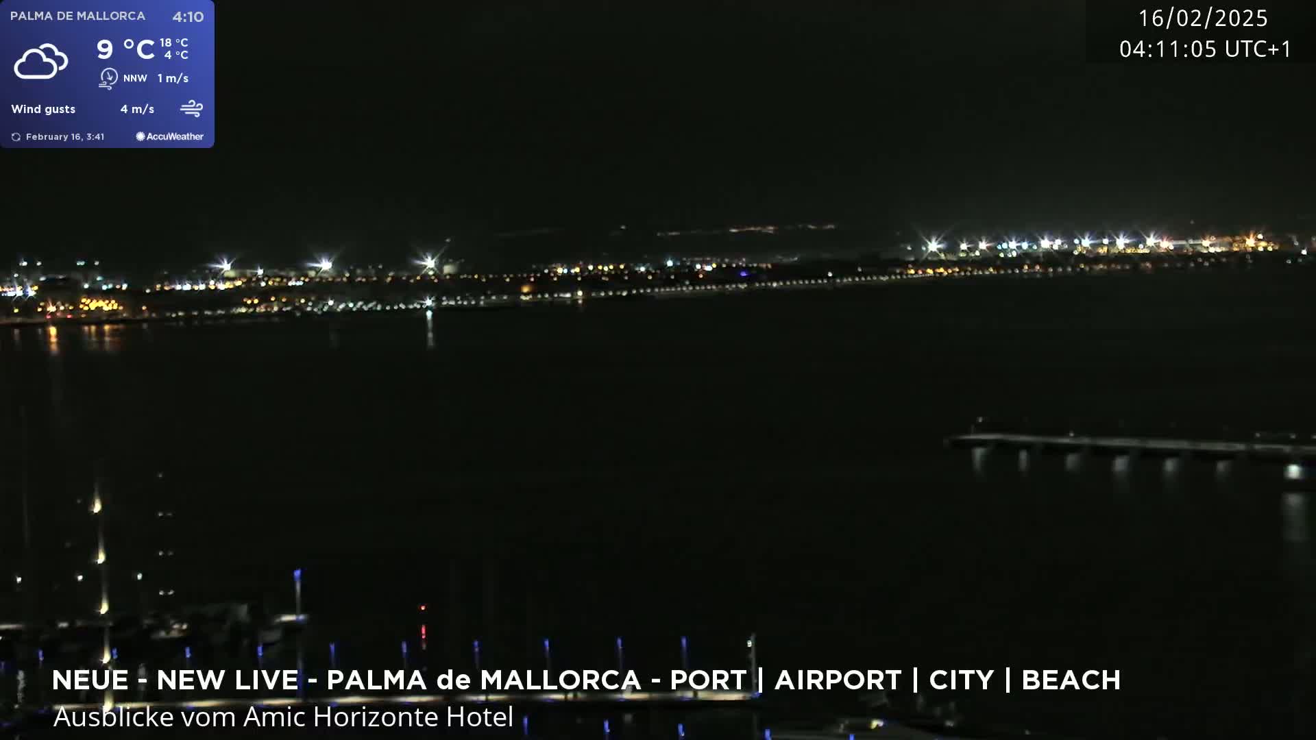 A nighttime view of a city skyline across a body of water, under partly cloudy skies with a light wind.