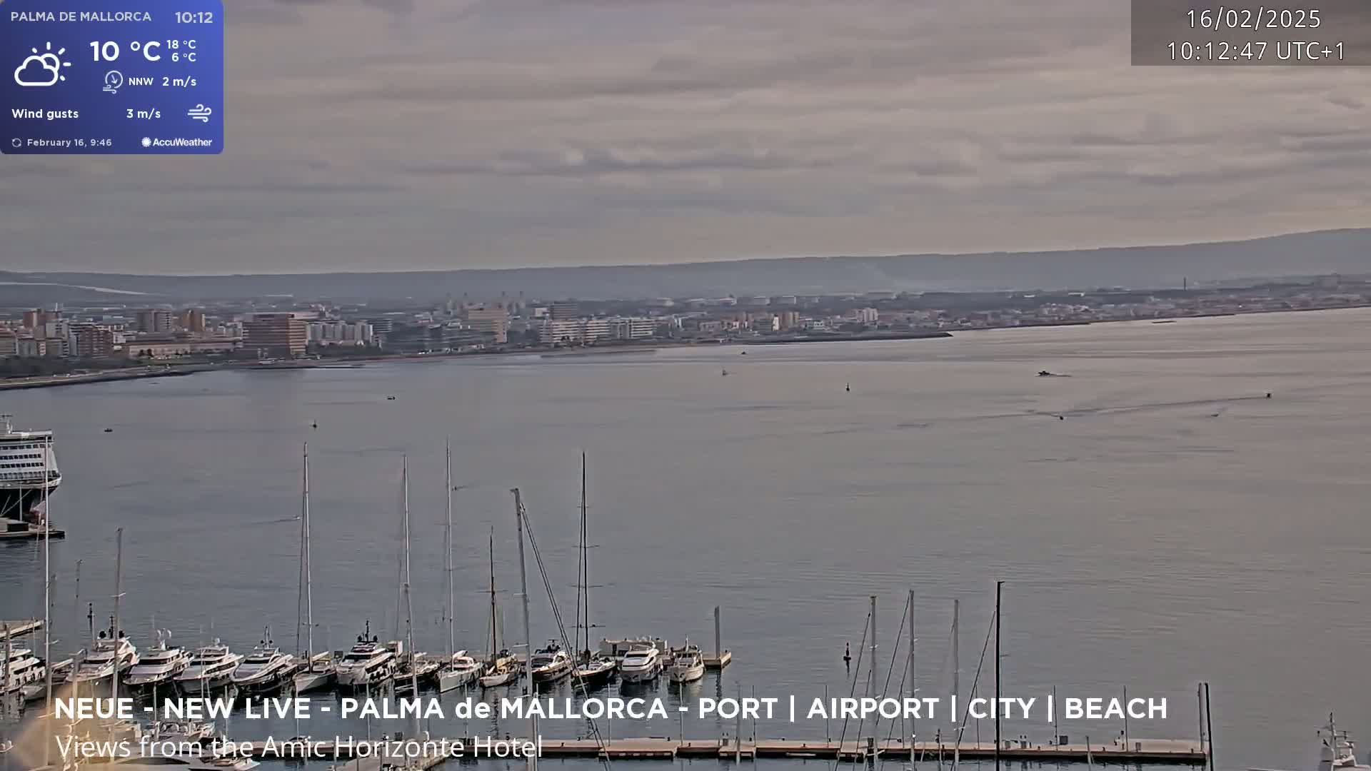 A partly cloudy day shows a city across a bay with many sailboats docked at a marina in the foreground.