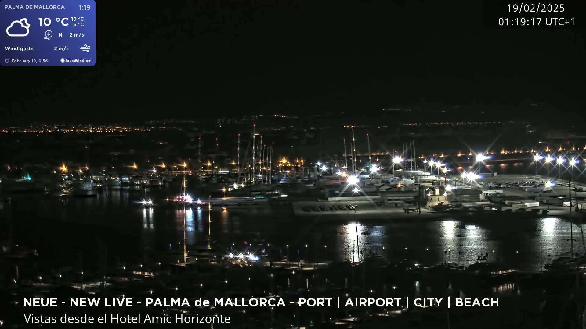 A nighttime harbor scene with numerous boats and lights reflecting on the calm water under a clear sky.