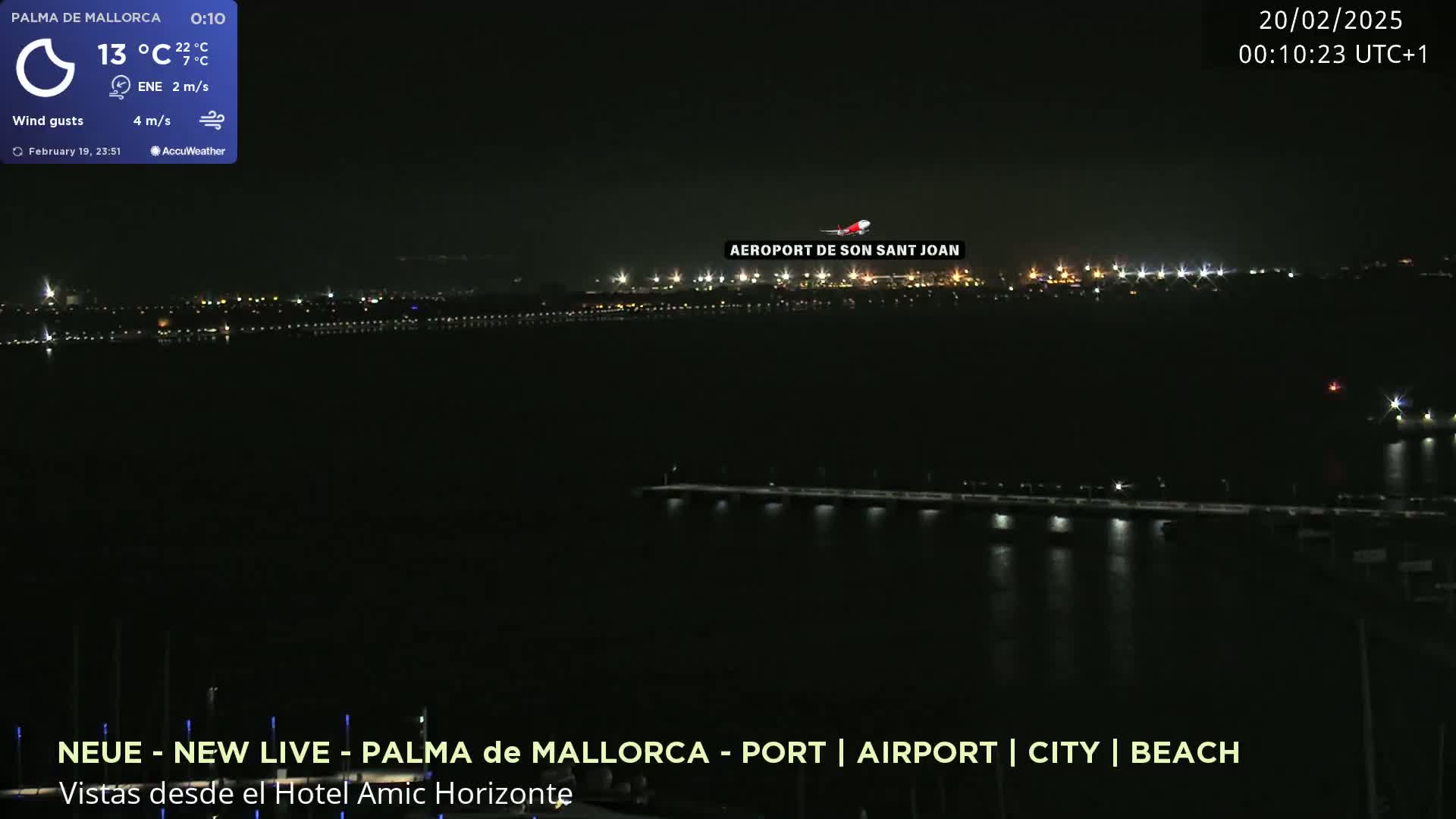 A nighttime view of an airport and city lights across a dark body of water under a clear sky.