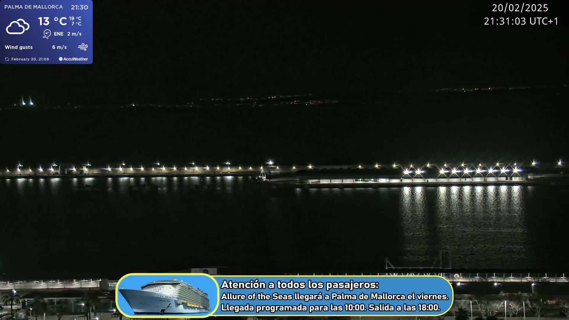 A nighttime view of a harbor with lights illuminating a pier and calm water under a clear sky.