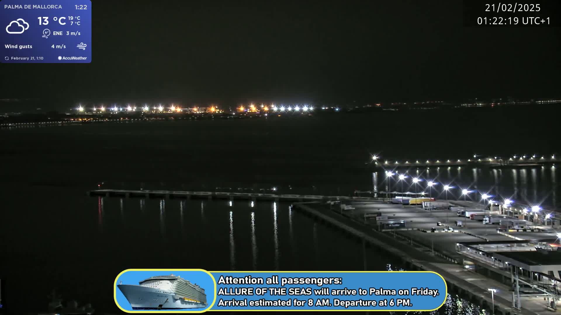 A nighttime harbor scene shows a dark body of water with lights illuminating a dock and a distant shoreline.