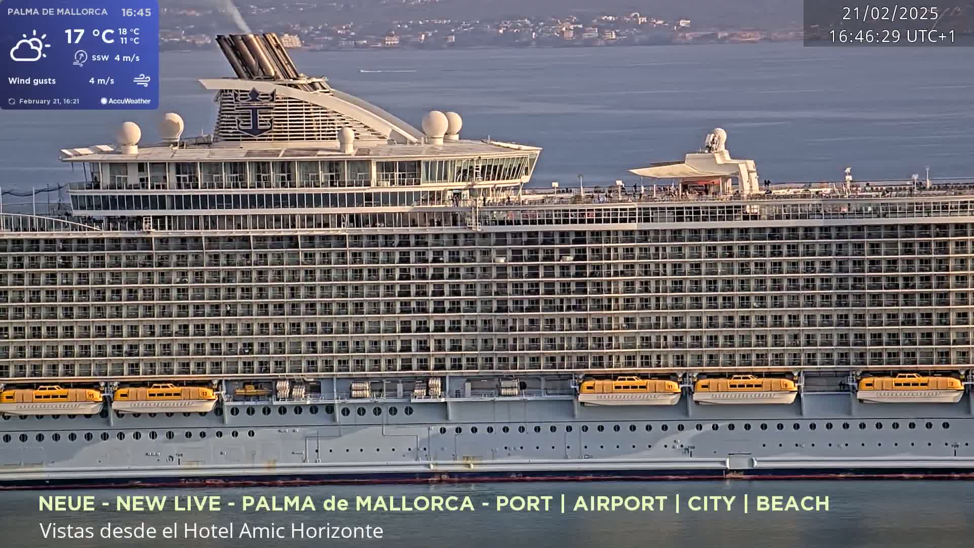 A large cruise ship is docked in calm water under a partly cloudy sky.