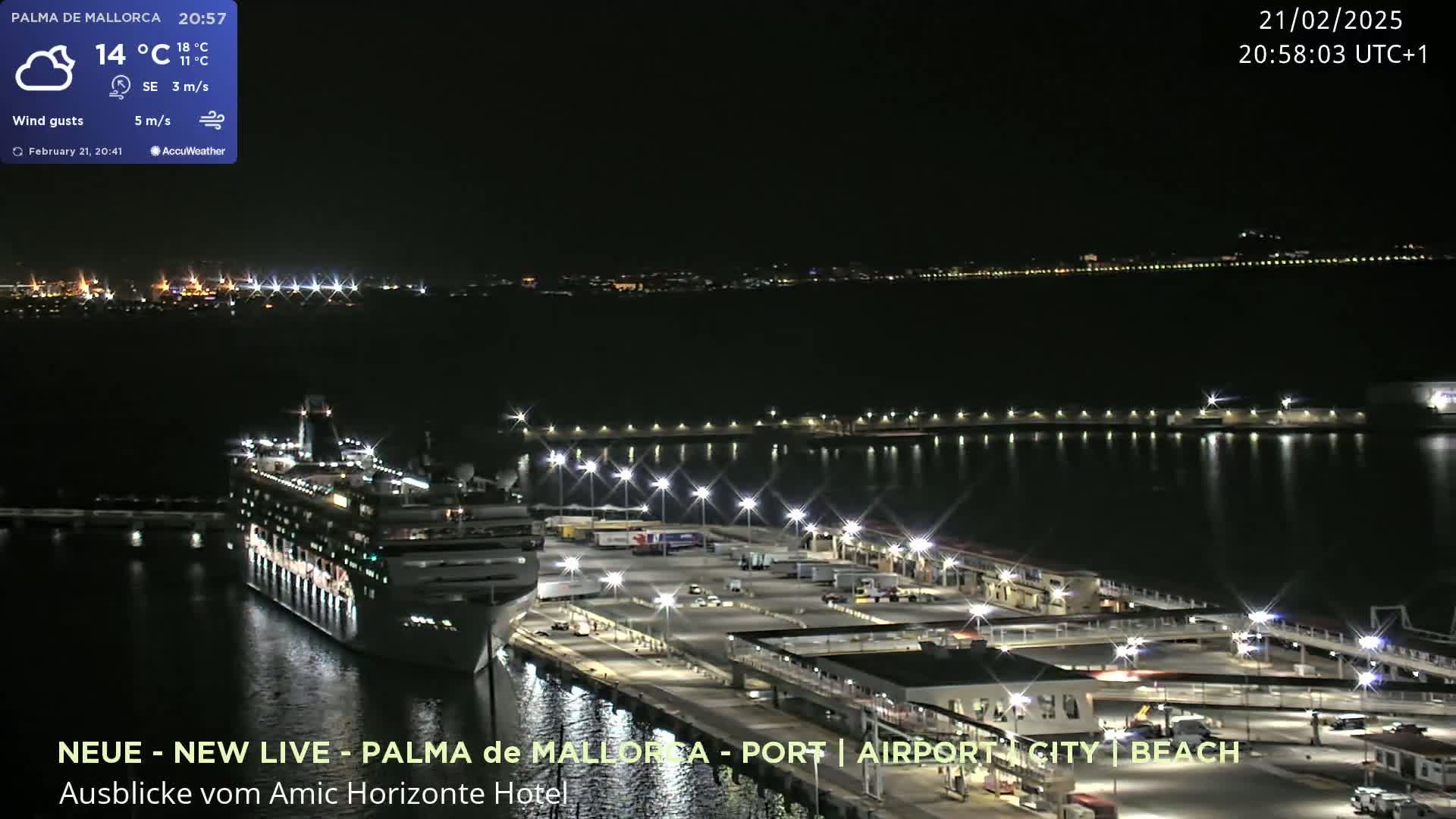 A cruise ship is docked at a brightly lit port at night under partly cloudy skies.