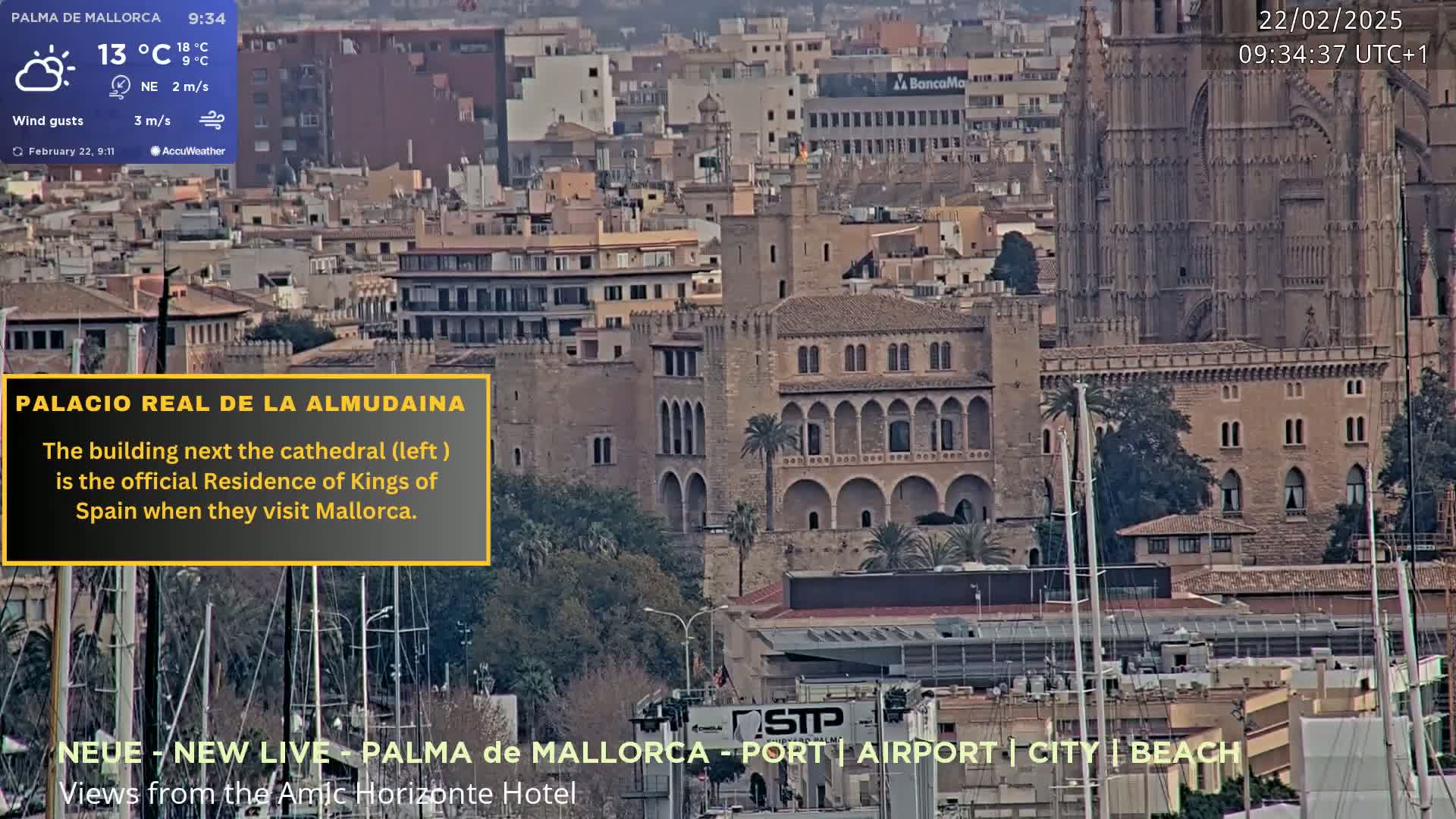 A partly cloudy cityscape with a large cathedral and adjacent palace overlooking a harbor filled with sailboats.