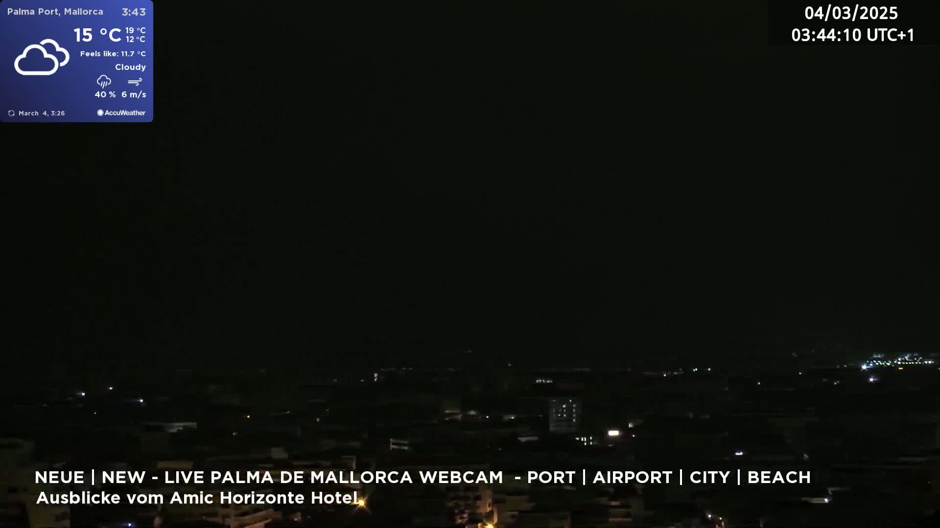 A nighttime, cloudy view of a city illuminated by scattered lights, with a gentle breeze.