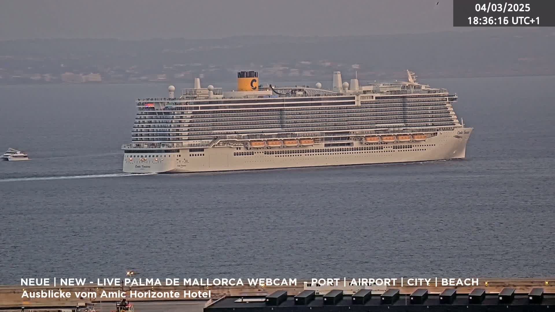 A large cruise ship sails on calm, gray water under an overcast sky.