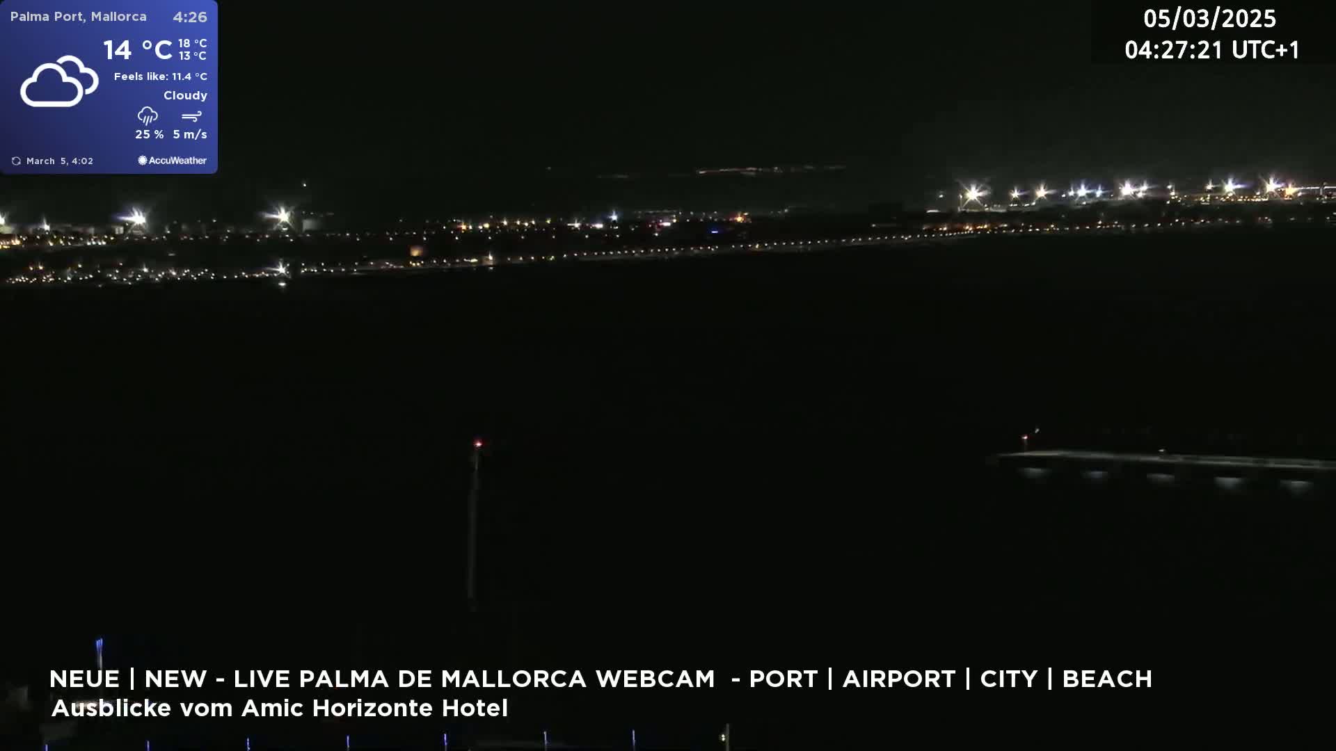 A nighttime, cloudy view of a city's lights across a dark body of water.