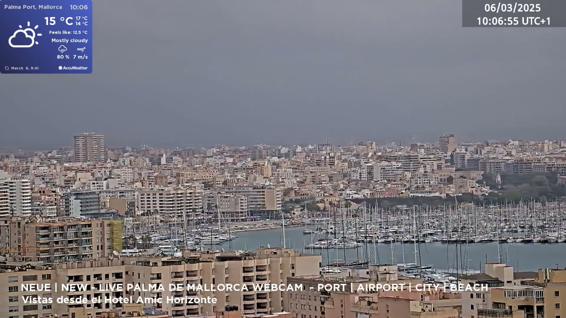 A mostly cloudy, breezy day overlooks a harbor filled with sailboats and a dense cityscape.