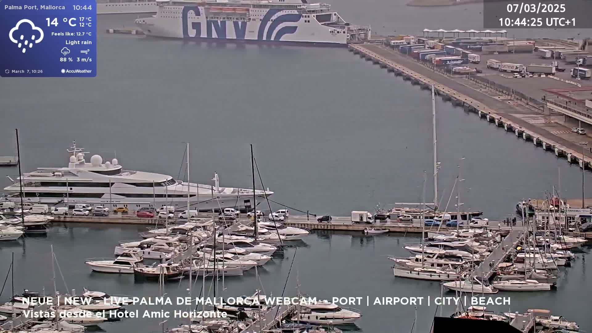 A harbor with numerous yachts and a large ferry in light rain.