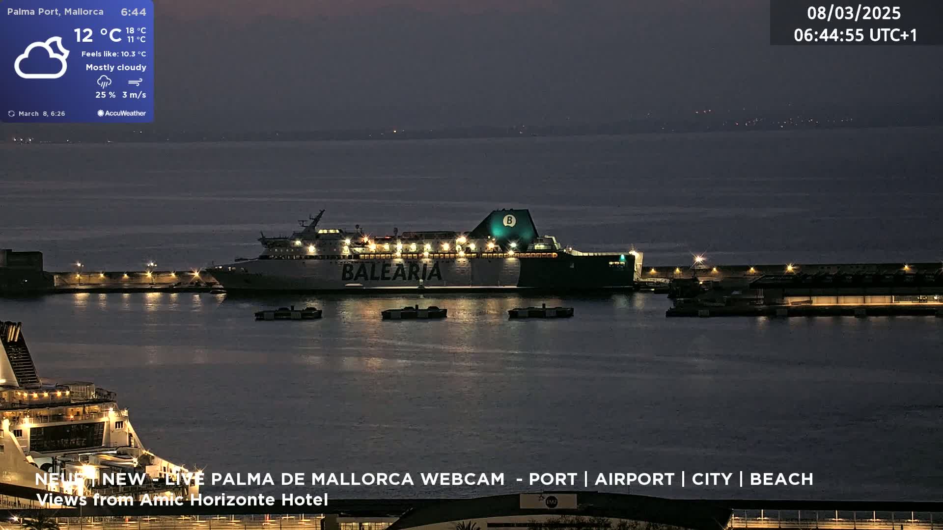 A large ferry, illuminated, sits in a mostly cloudy, dark harbor at night.
