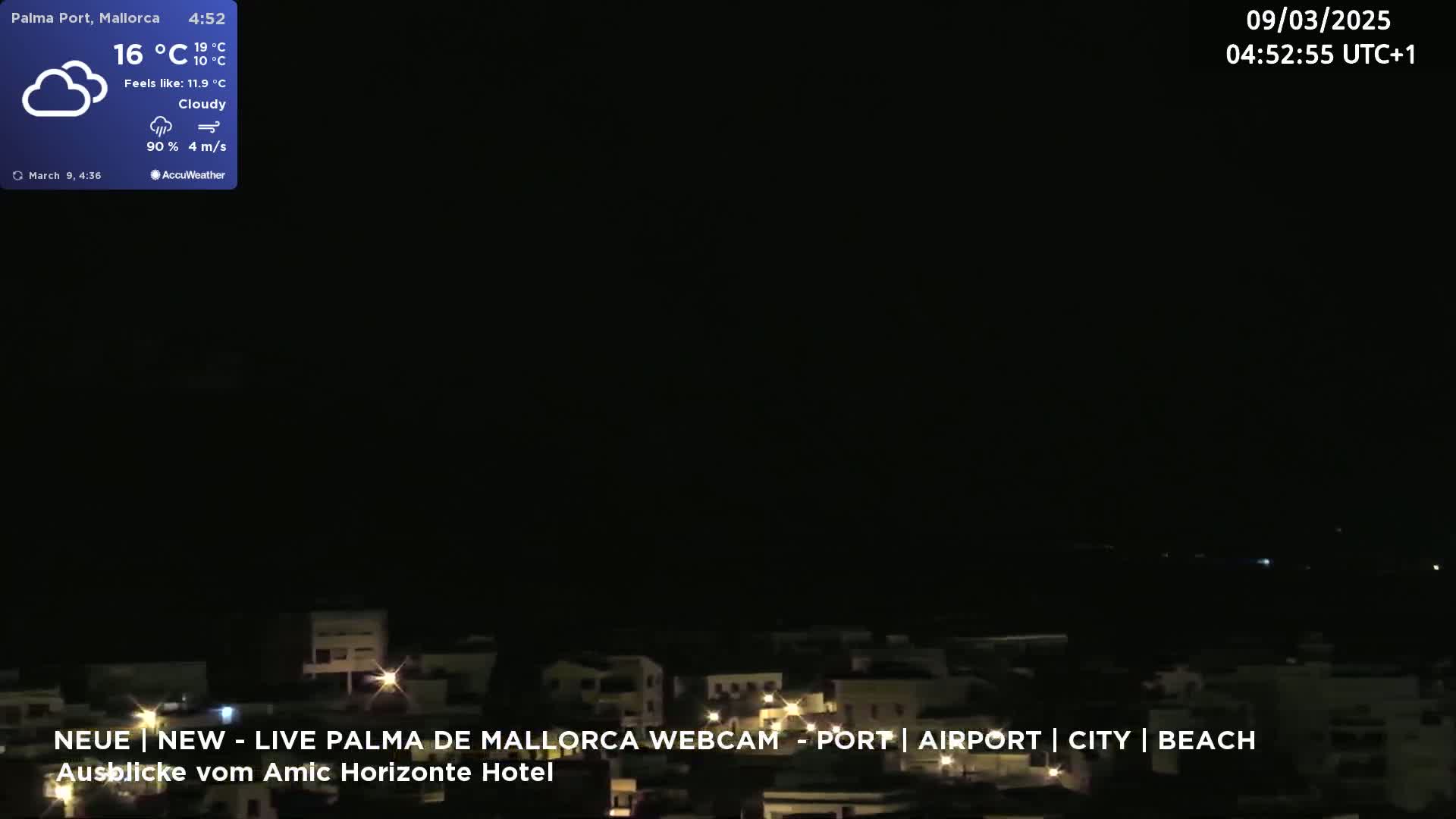 A nighttime view of a city illuminated by lights, under cloudy skies.