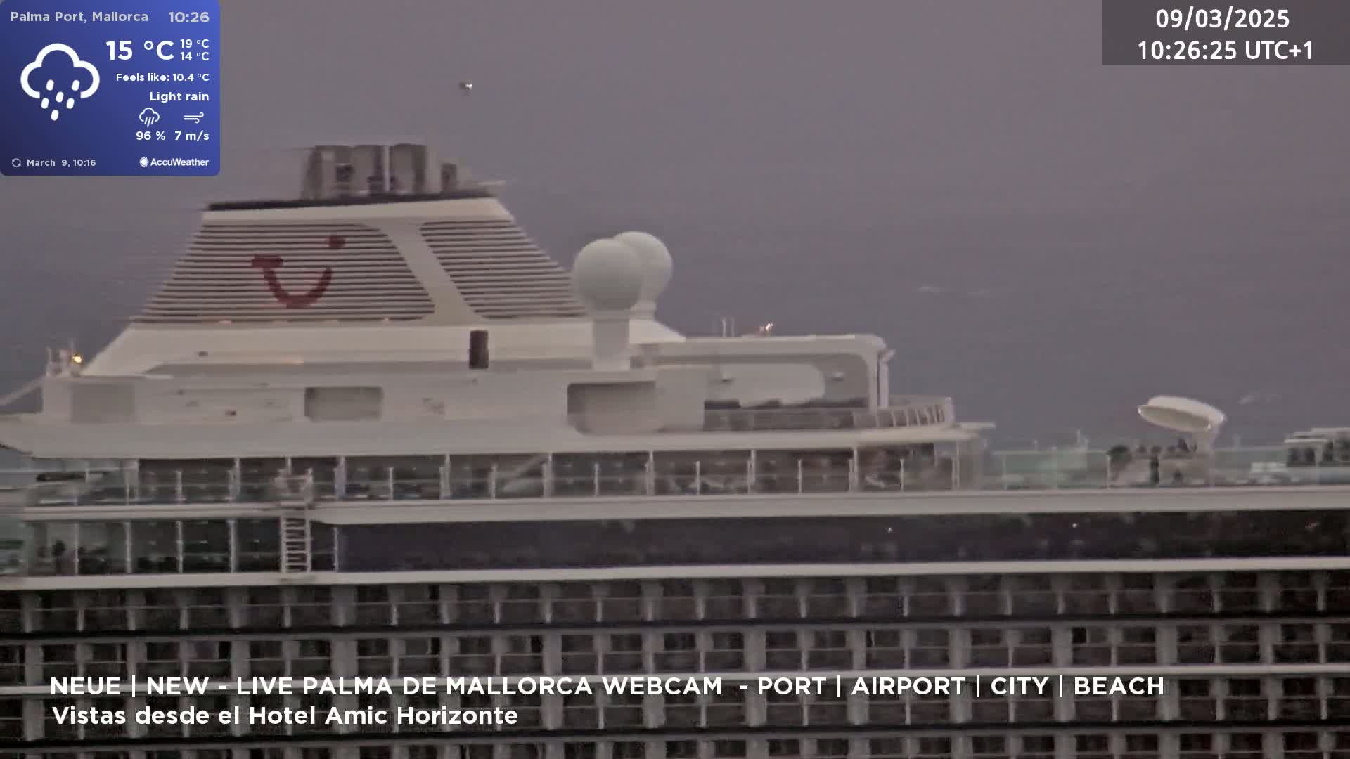 A large cruise ship is seen under a light rain in overcast conditions.