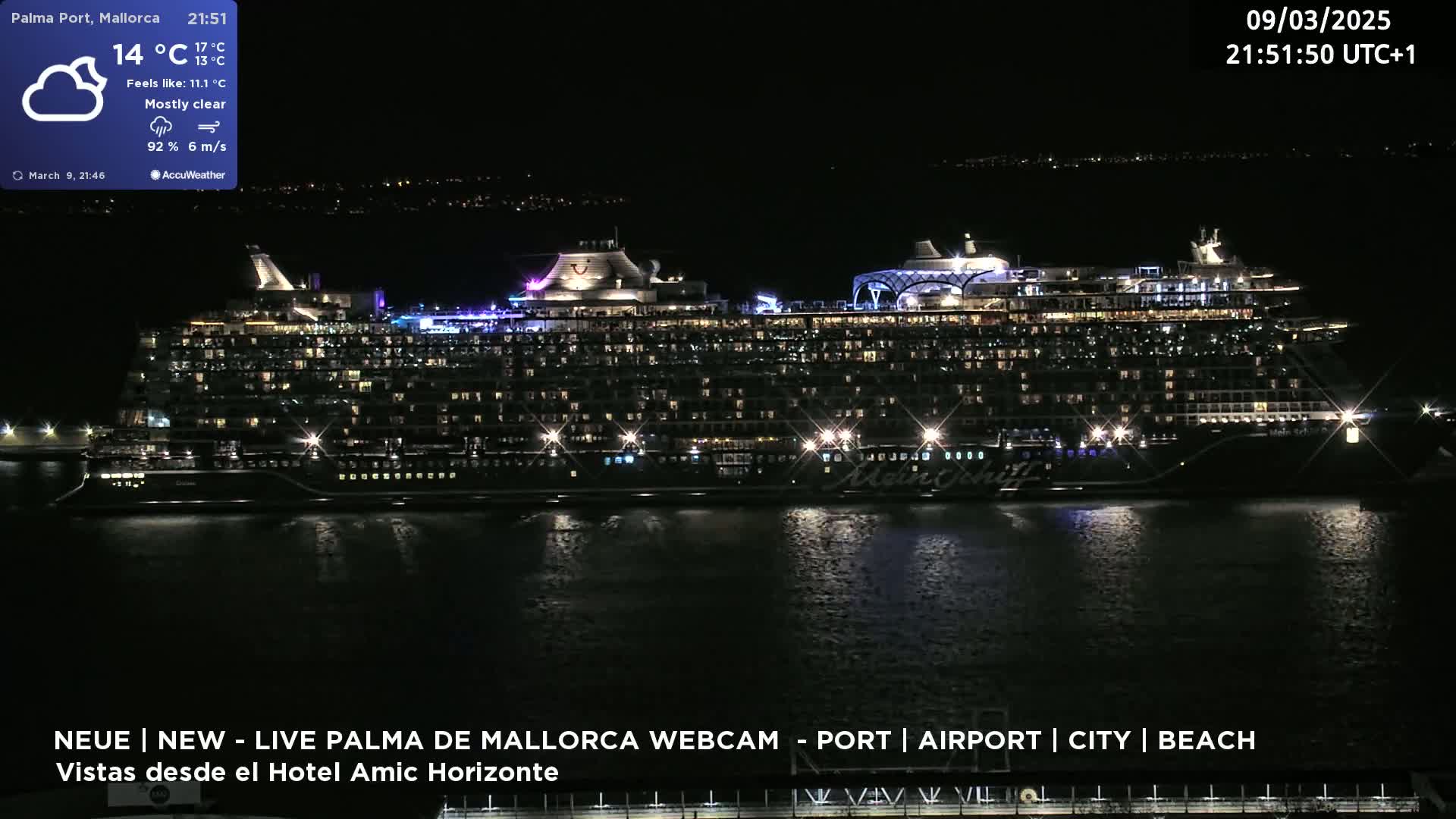 A large cruise ship is docked at a port at night under mostly clear skies.