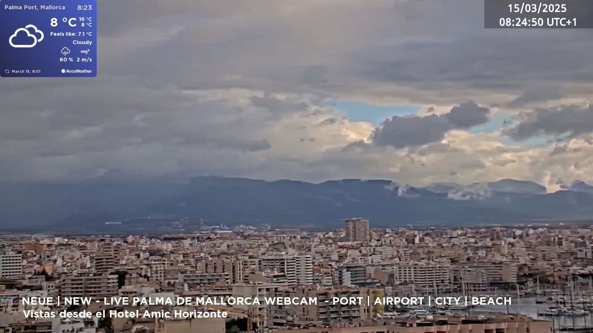 A cloudy view of a city with mountains in the background.