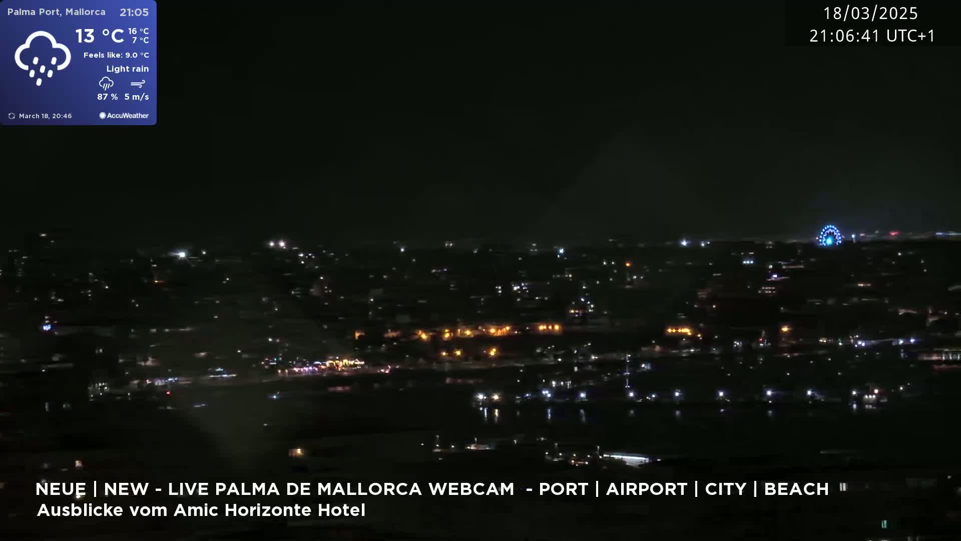 A nighttime, aerial view of a city with a Ferris wheel visible in the distance under light rain.