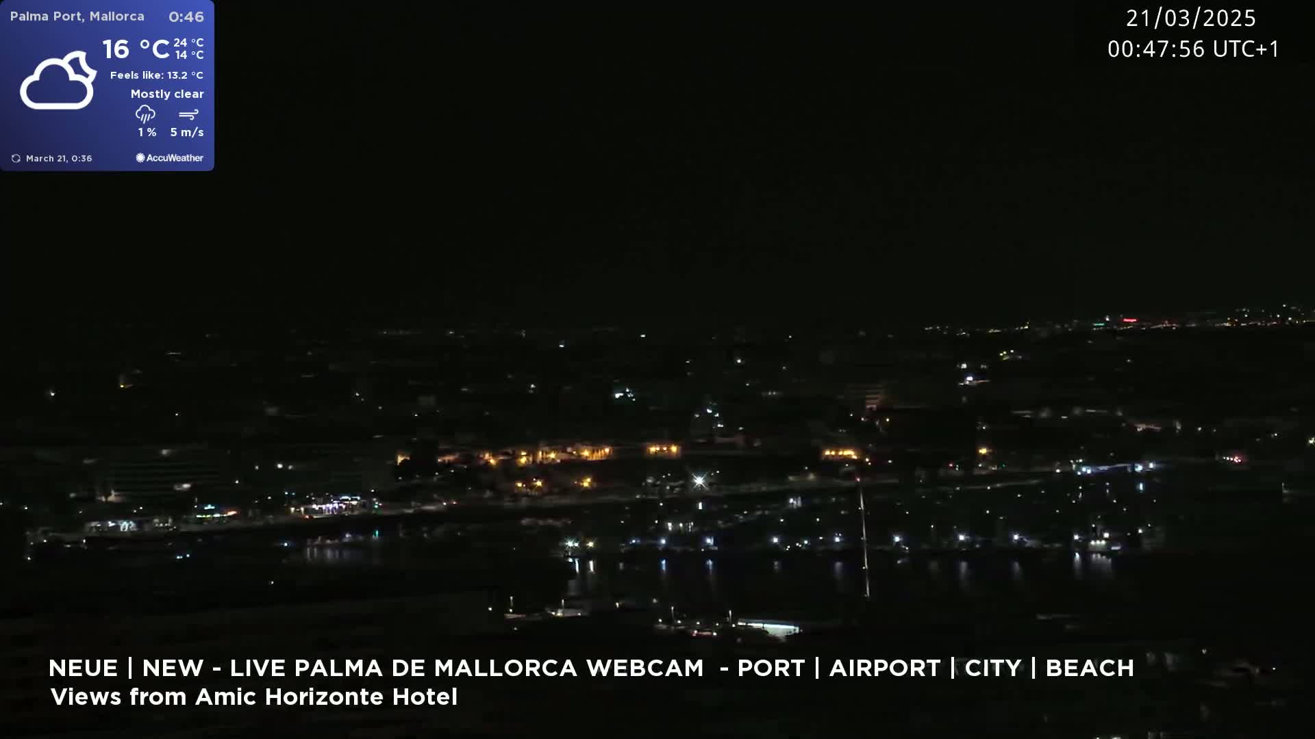 A nighttime, mostly clear view of a city's harbor and lights spread across the dark landscape.