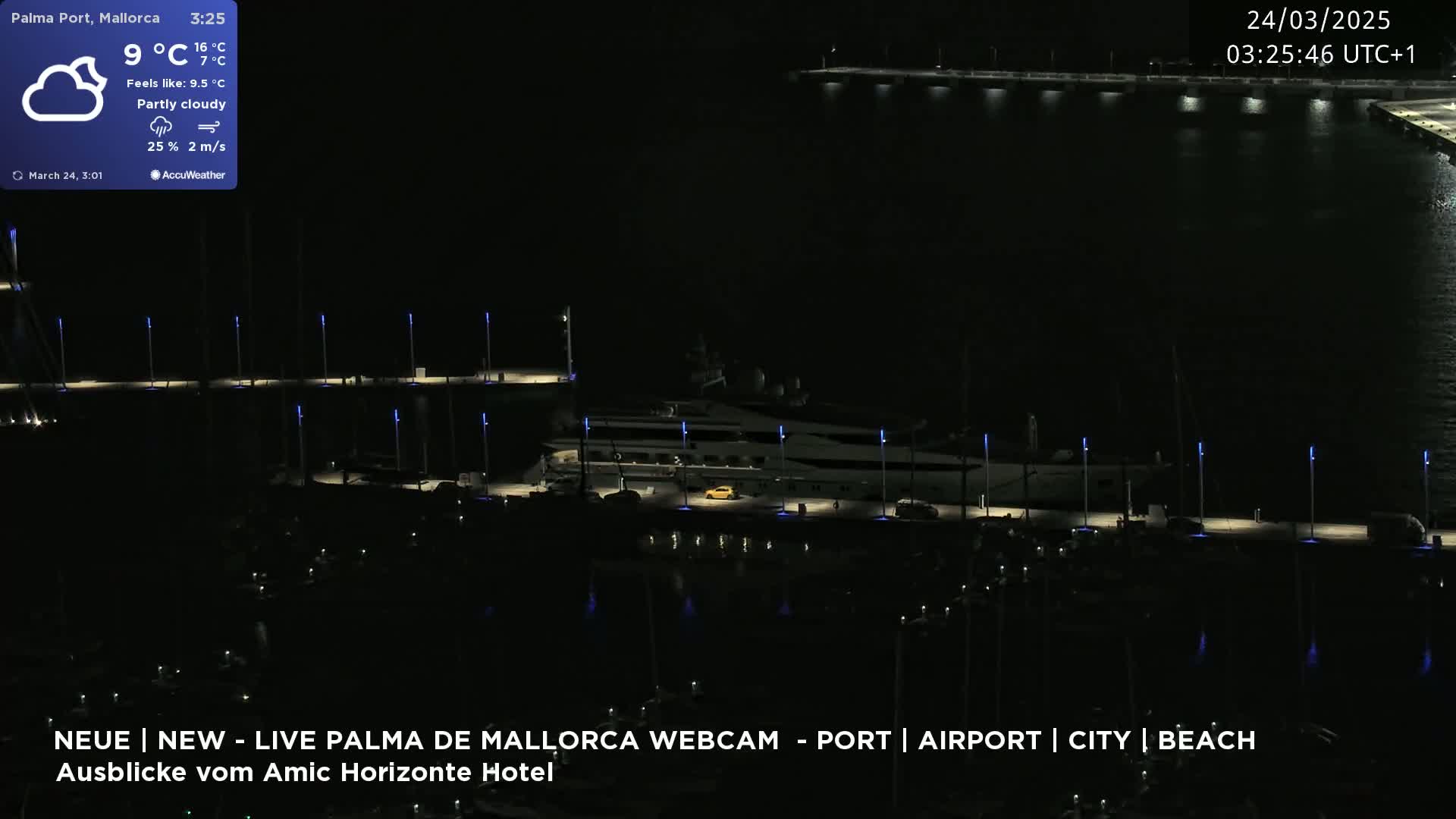 A large yacht is docked at a marina at night under partly cloudy skies.