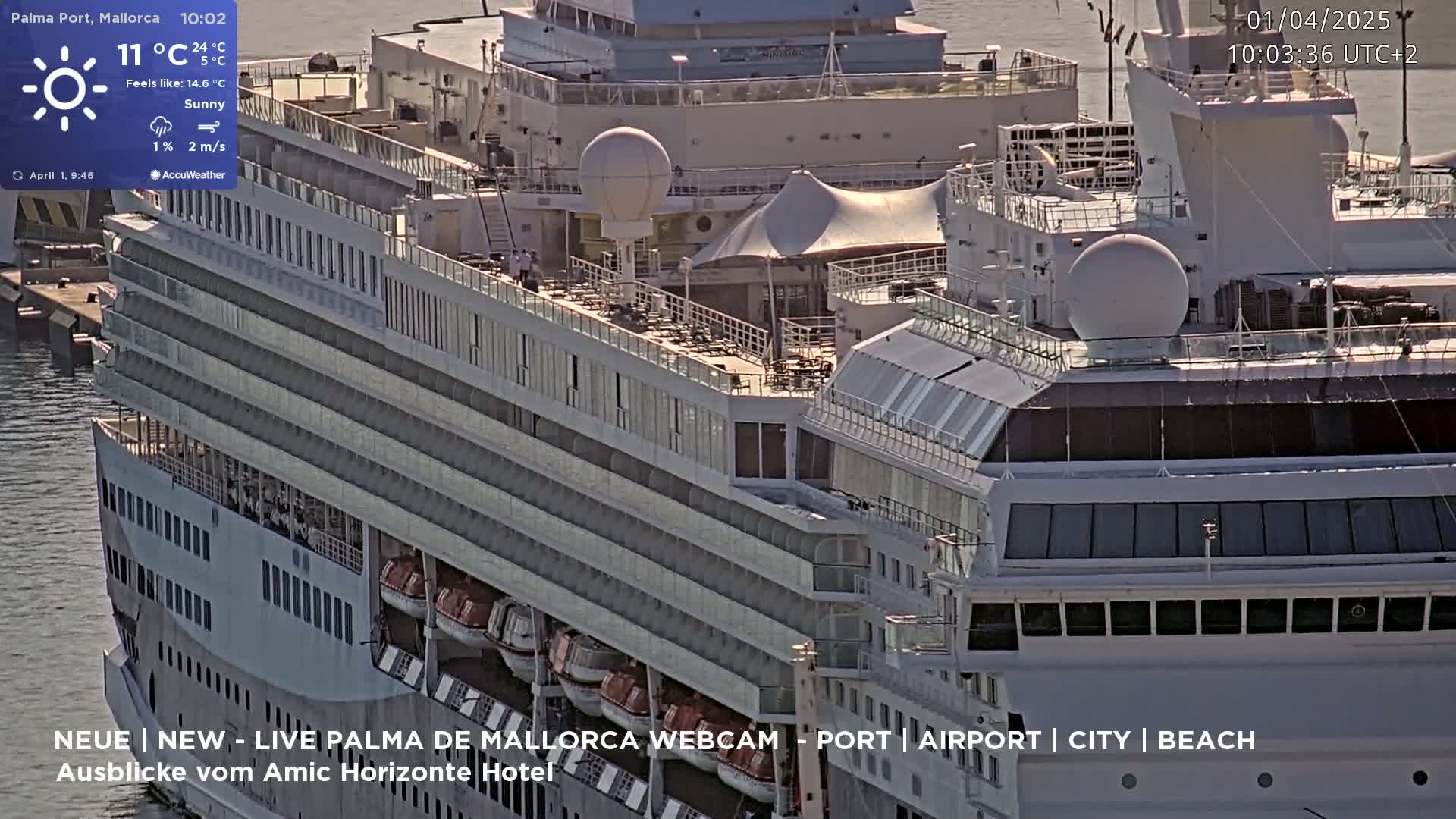 A large cruise ship is docked at a port on a sunny day with a light breeze.