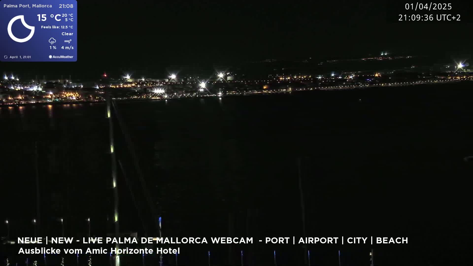 A nighttime view of a city's lights across a dark body of water under a clear sky.
