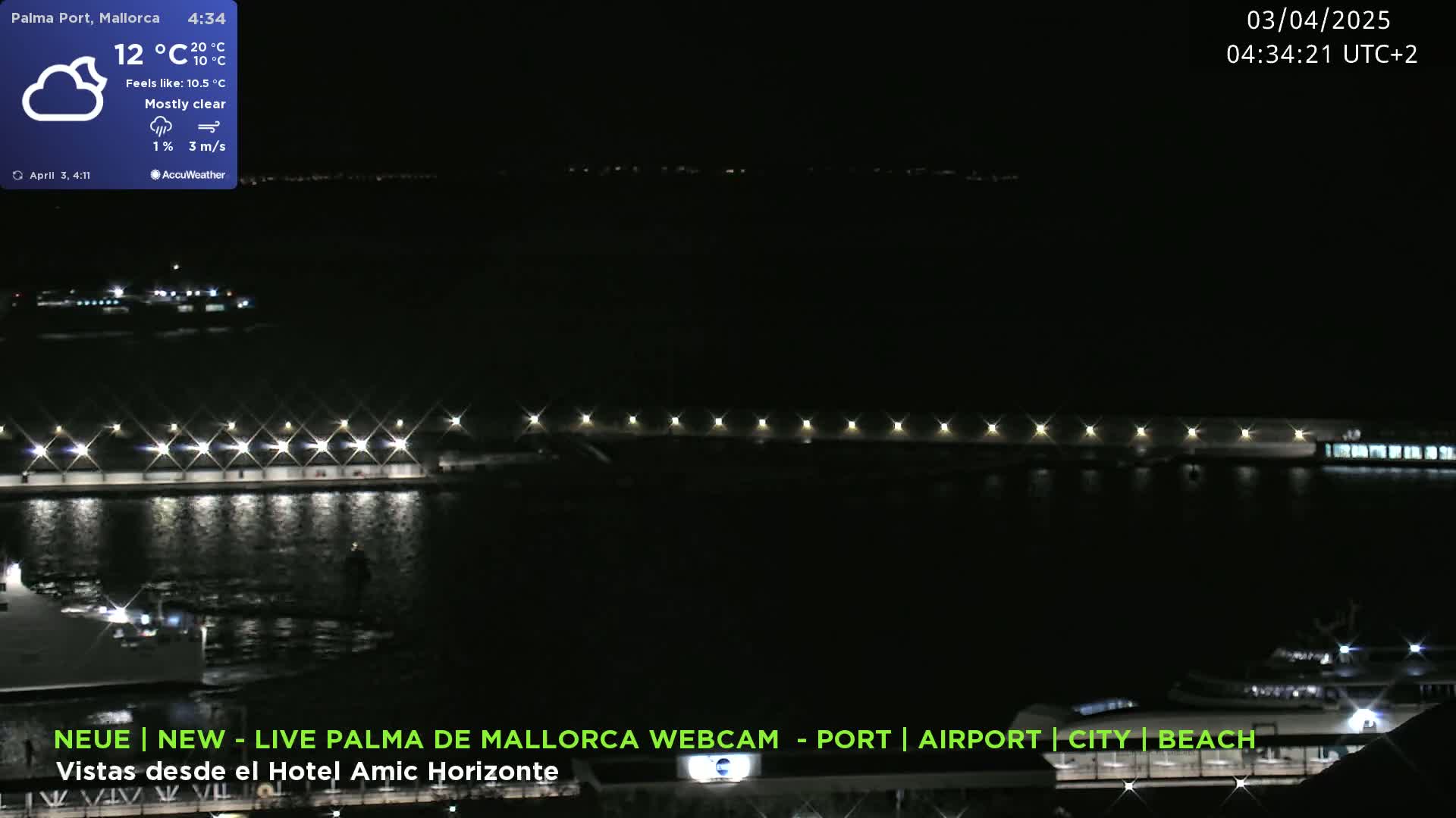 A nighttime harbor scene with mostly clear skies and calm water, illuminated by lights along a pier.