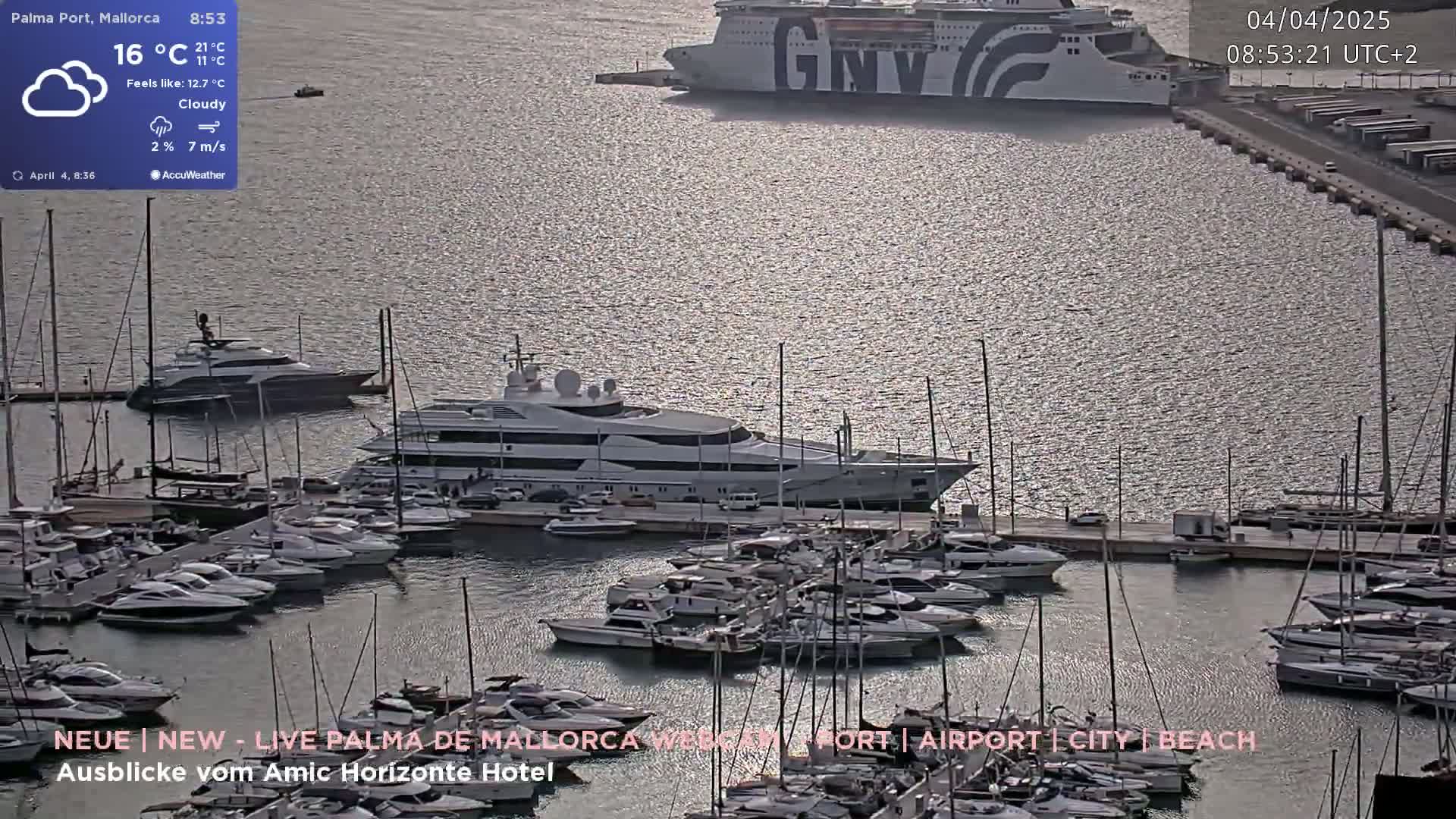 A marina filled with numerous yachts and boats on a cloudy day, with a large ferry docked in the background.