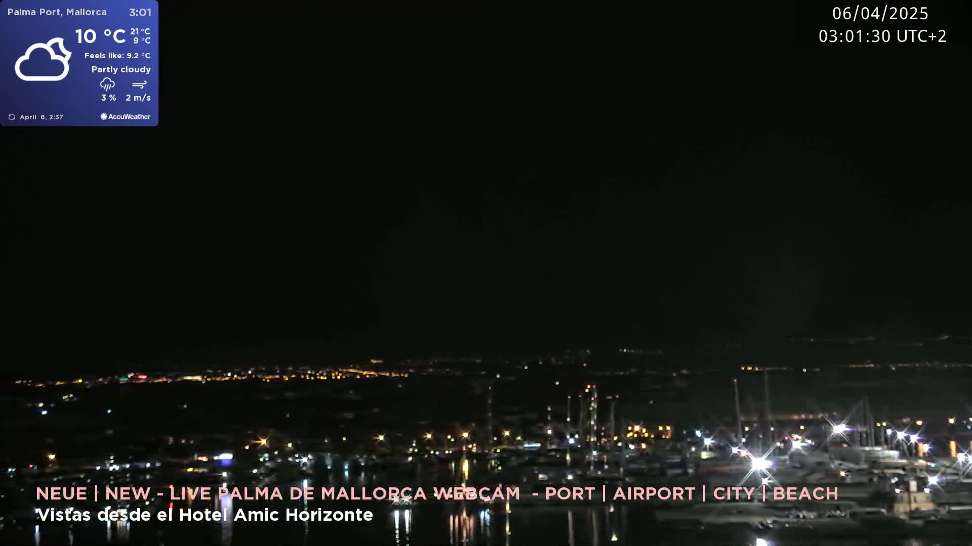 A nighttime, partly cloudy view of a city harbor illuminated with lights.