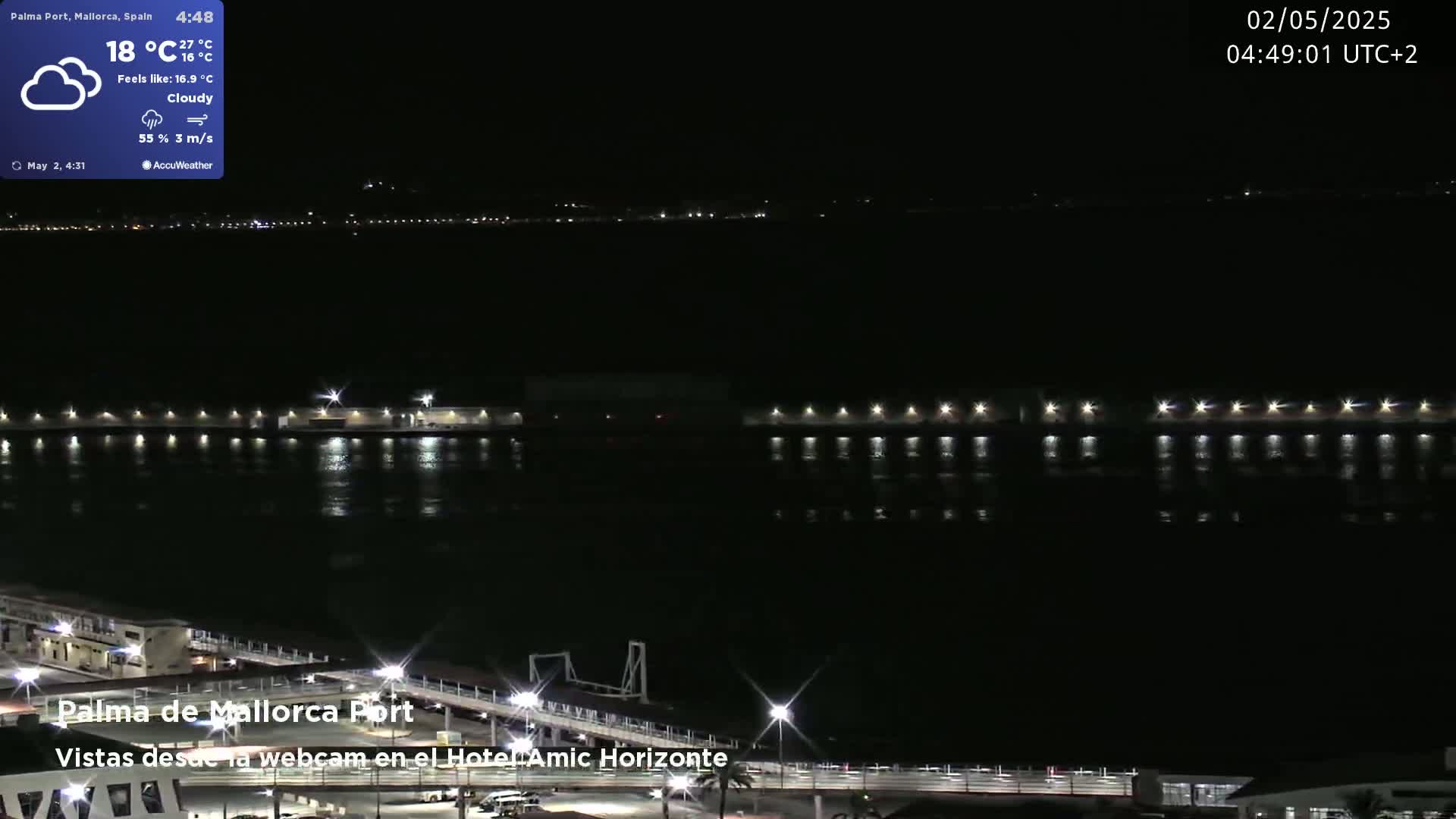 A nighttime, cloudy view of a harbor with lights reflecting on the water.