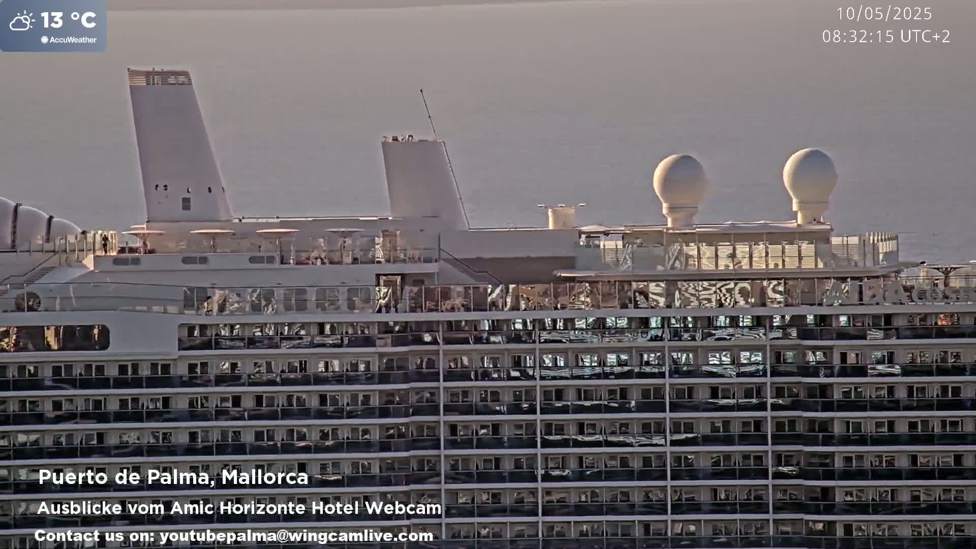 A large cruise ship is docked at sea on a partly sunny day with a calm sea.