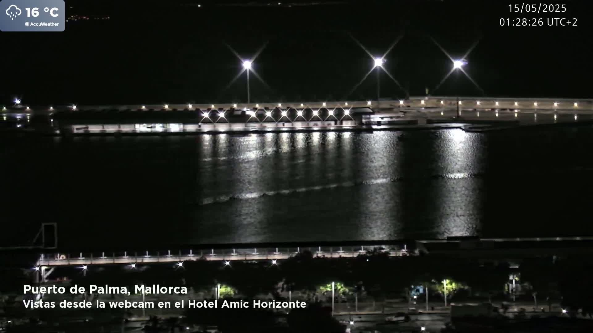 A nighttime view of a brightly lit harbor with calm water reflecting the lights.