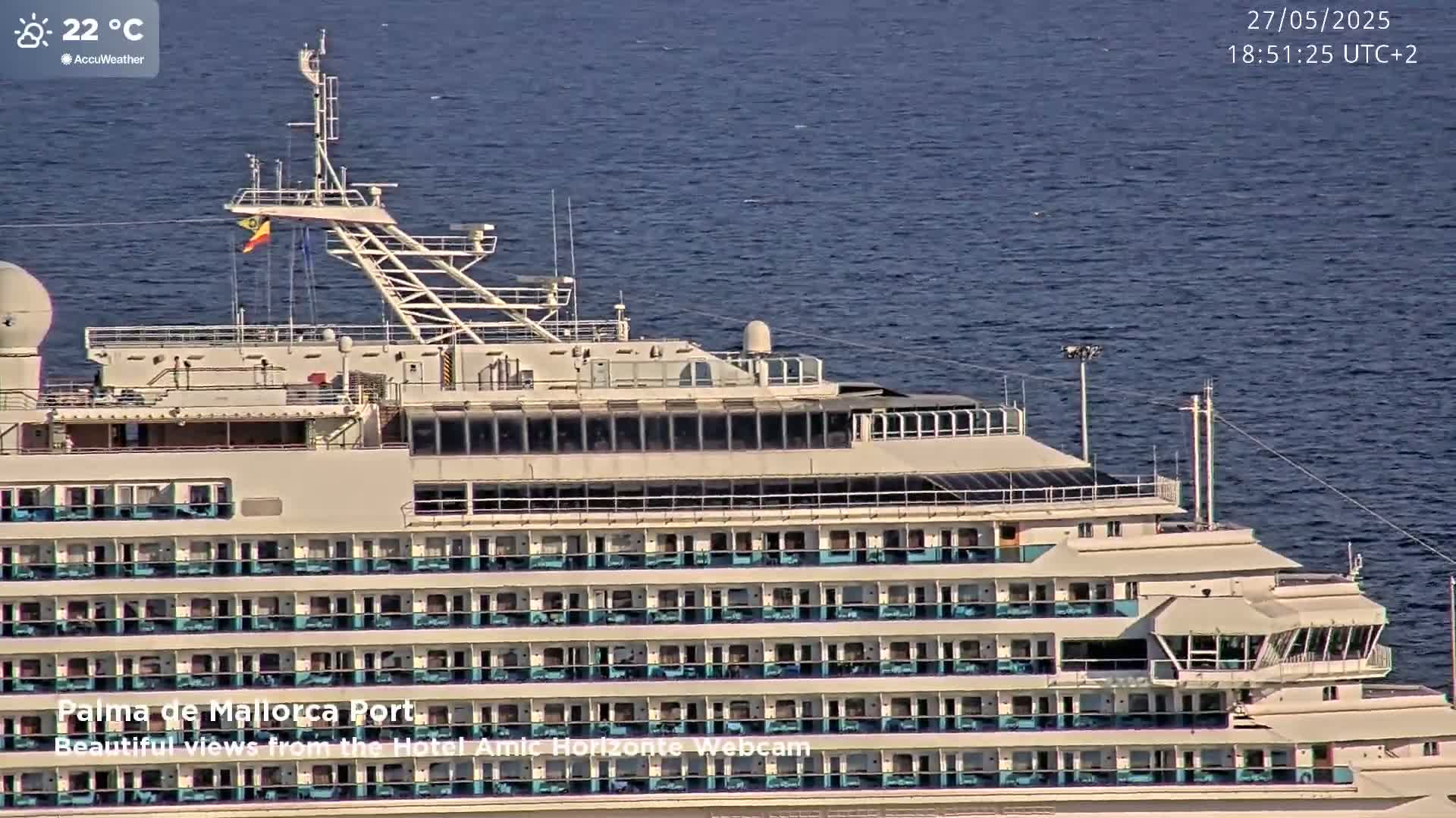 A large cruise ship is docked in calm waters on a sunny day.