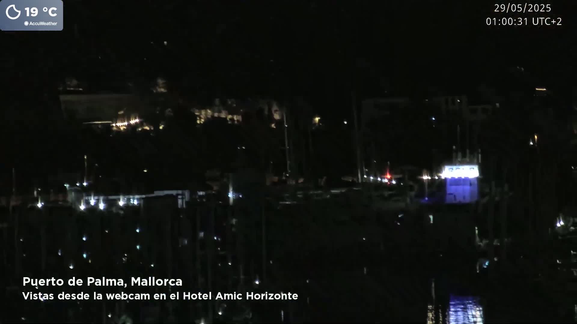 A nighttime view of a harbor filled with boats, illuminated by faint lights under a clear, dark sky.