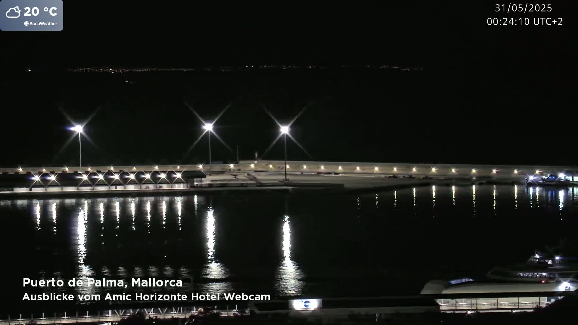 A nighttime view of a harbor with lights reflecting on calm water under a clear sky.