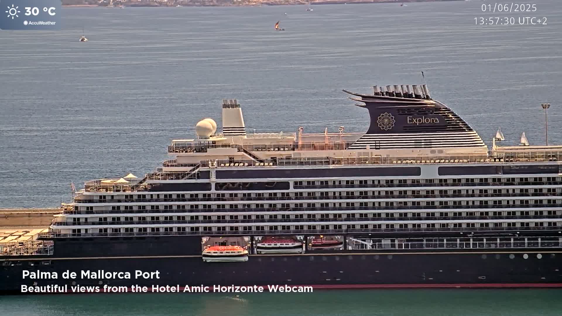 A large cruise ship named Explora is docked in calm water on a sunny day with a temperature of 30°C.