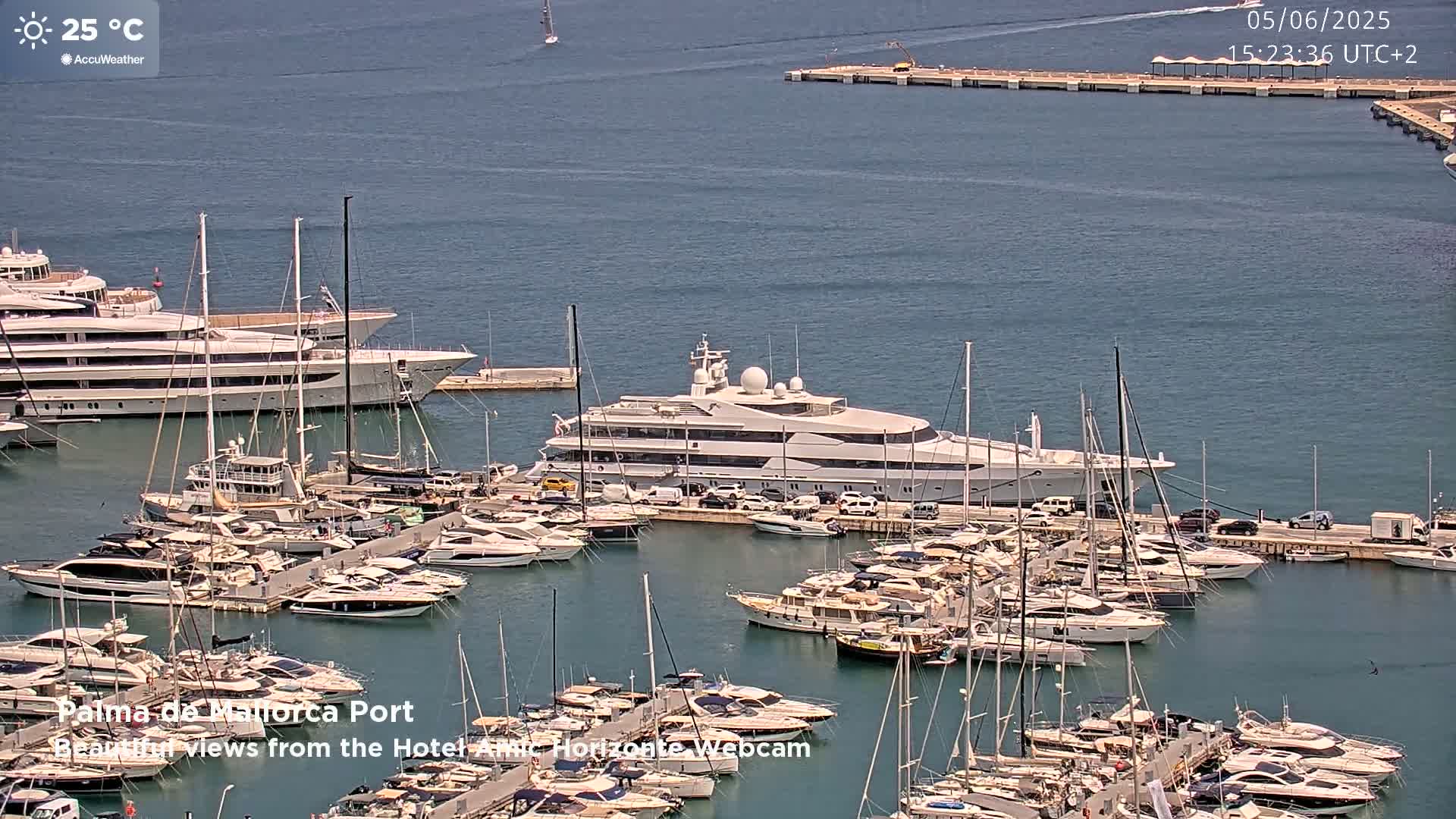 A large marina filled with yachts and sailboats on a sunny day with calm water.
