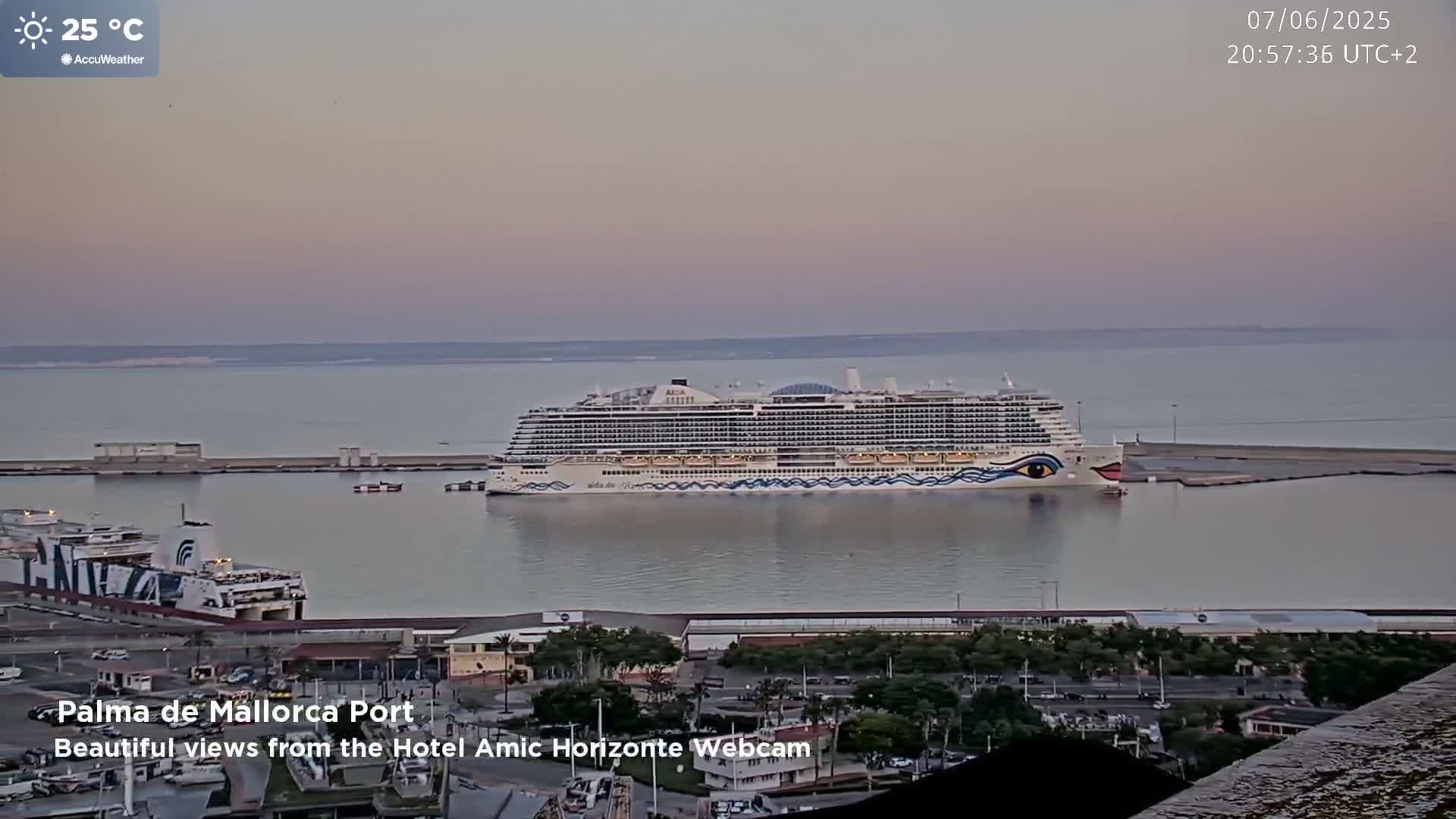 A large cruise ship is docked at a port under a calm, dusky sky.