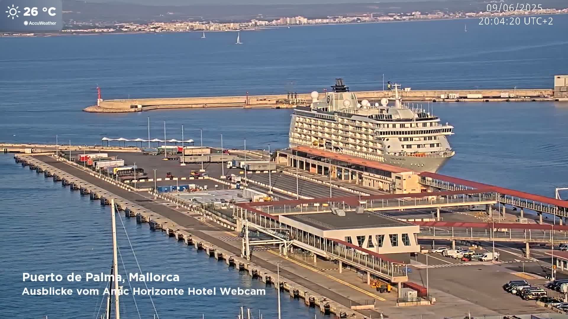 A large cruise ship is docked at a port on a sunny day with calm waters.
