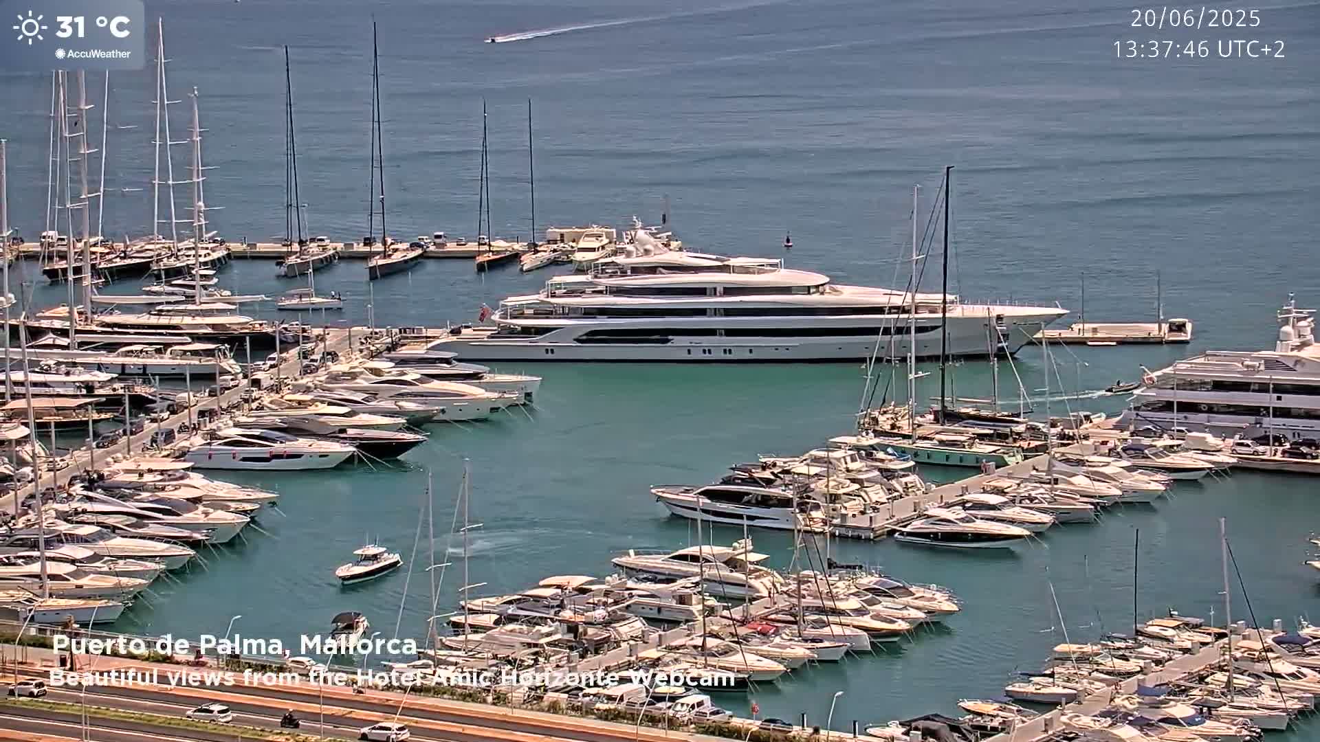 A marina filled with numerous yachts and sailboats on a sunny day with a temperature of 31 degrees Celsius.