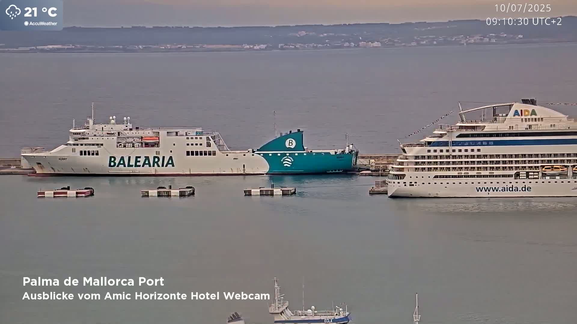 A large ferry and a cruise ship are docked in a calm harbor under an overcast sky.