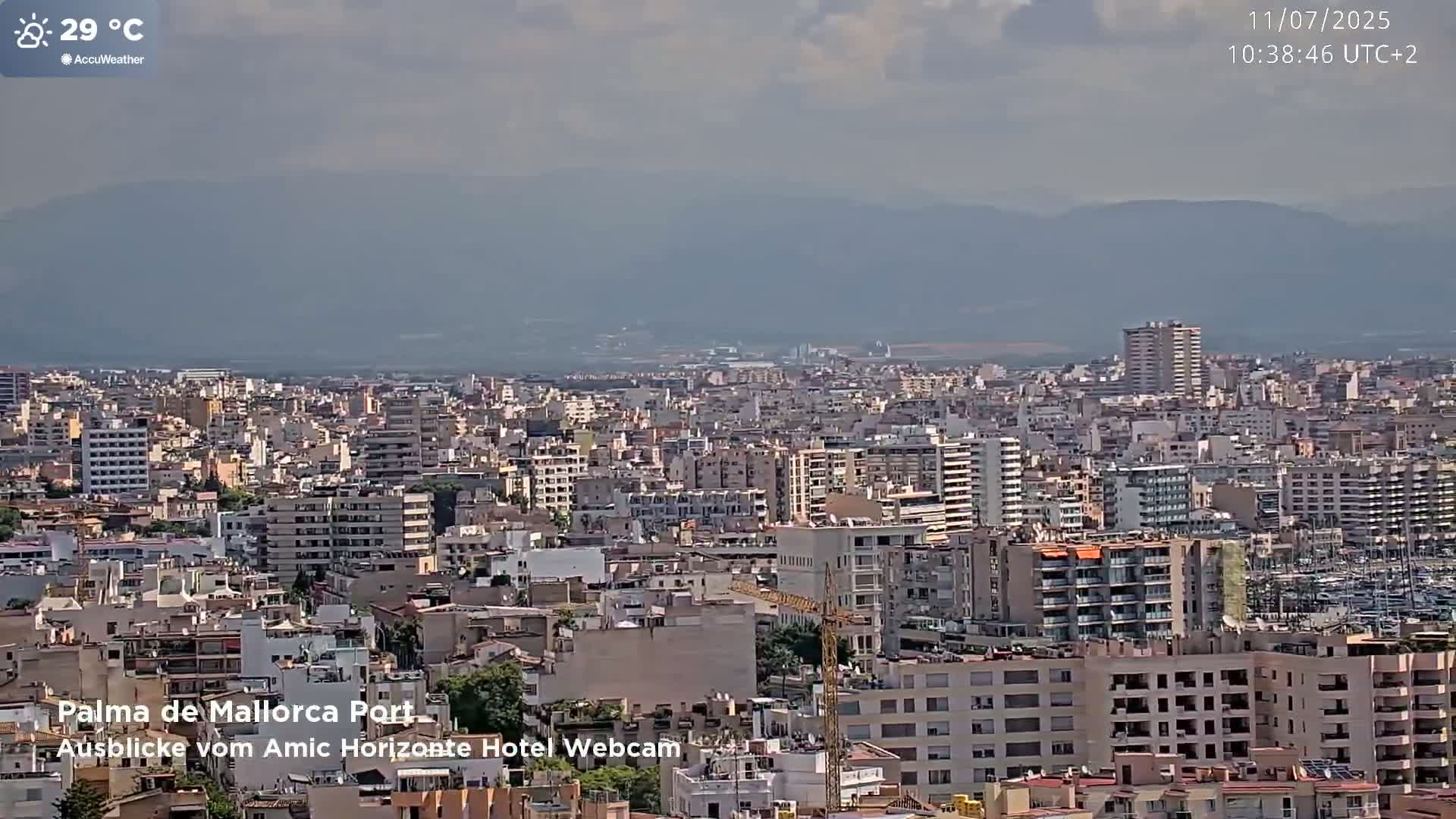 A hazy, sunny day reveals a sprawling cityscape nestled against a distant mountain range.