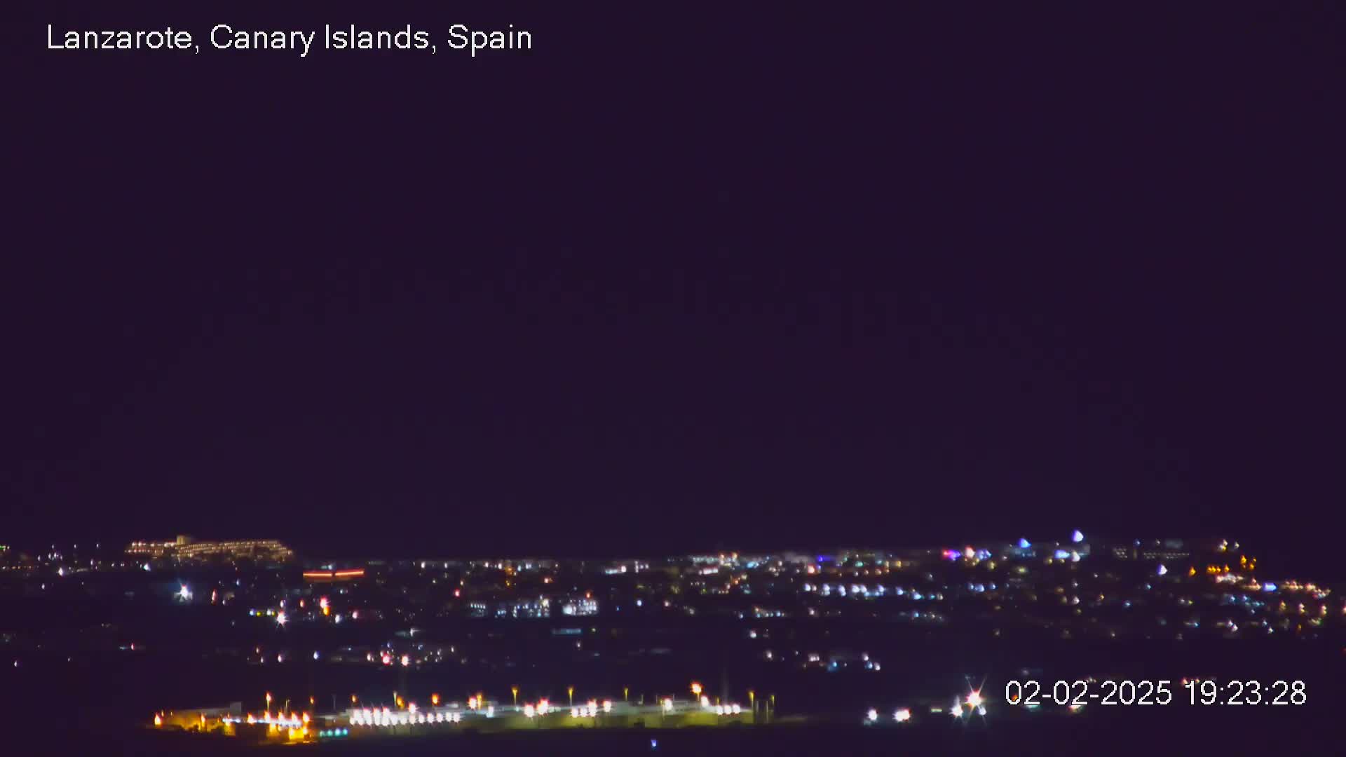 A nighttime long shot of a city illuminated by many small lights under a clear, dark sky.