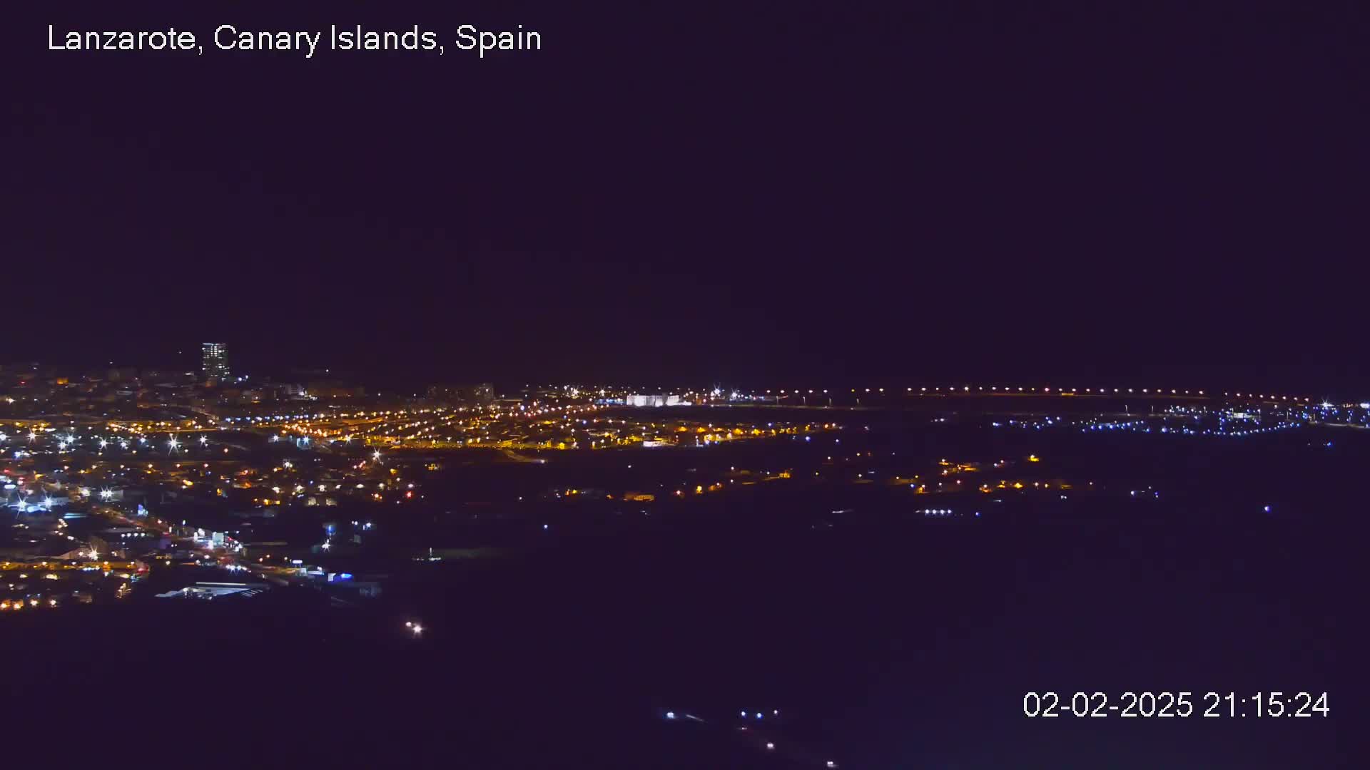 A nighttime aerial view shows a city illuminated by many small lights, under a clear, dark sky.